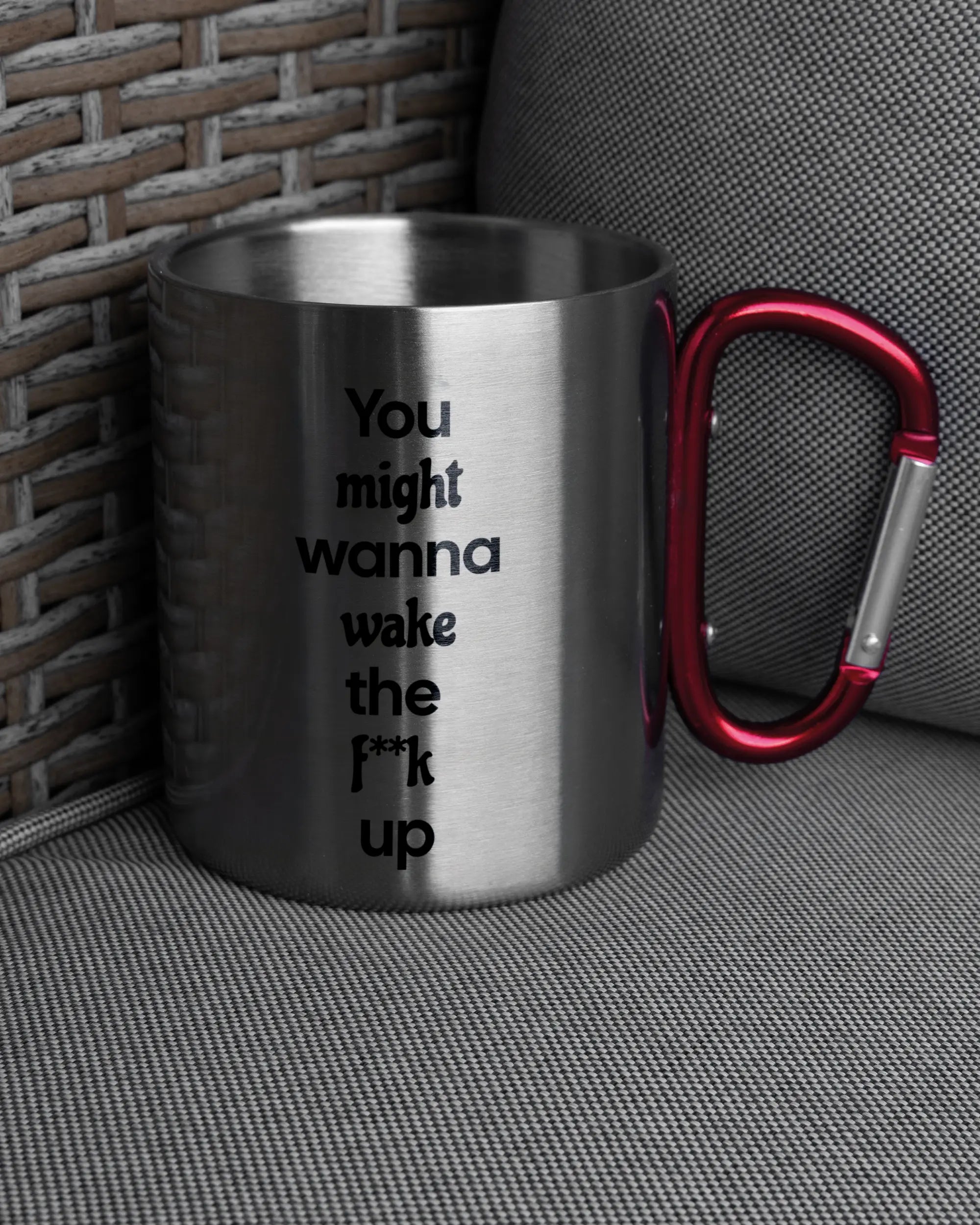 Ansicht der rechten Seite der beidseitig bedruckten Edelstahltasse von Maondo auf einem Balkonmöbel bzw. Campingstuhl mit dem Design Wanna Wake in der Farbe Metallic-Red