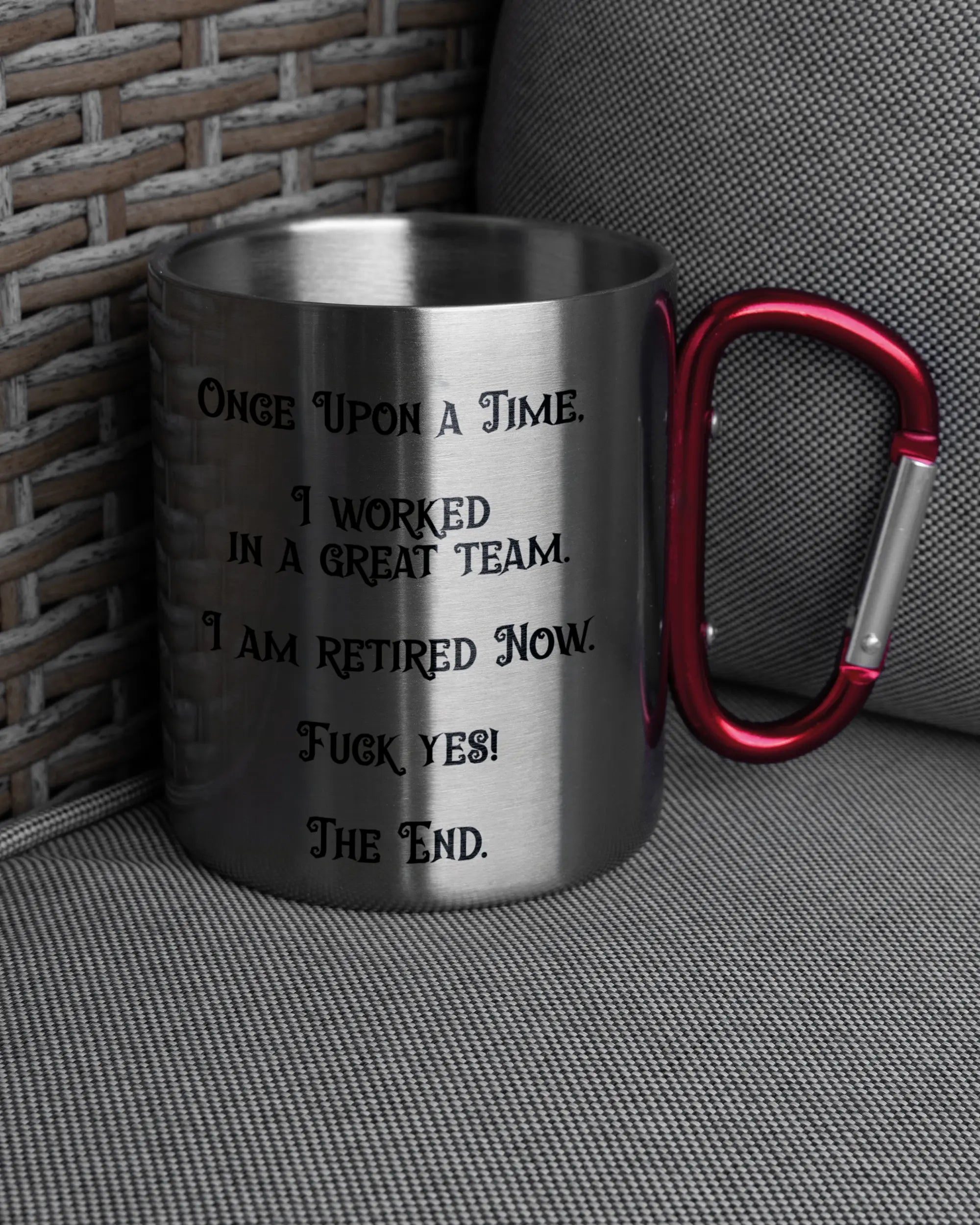 Ansicht der rechten Seite der beidseitig bedruckten Edelstahltasse von Maondo auf einem Balkonmöbel bzw. Campingstuhl mit dem Design Finally Retired in der Farbe Metallic-Red