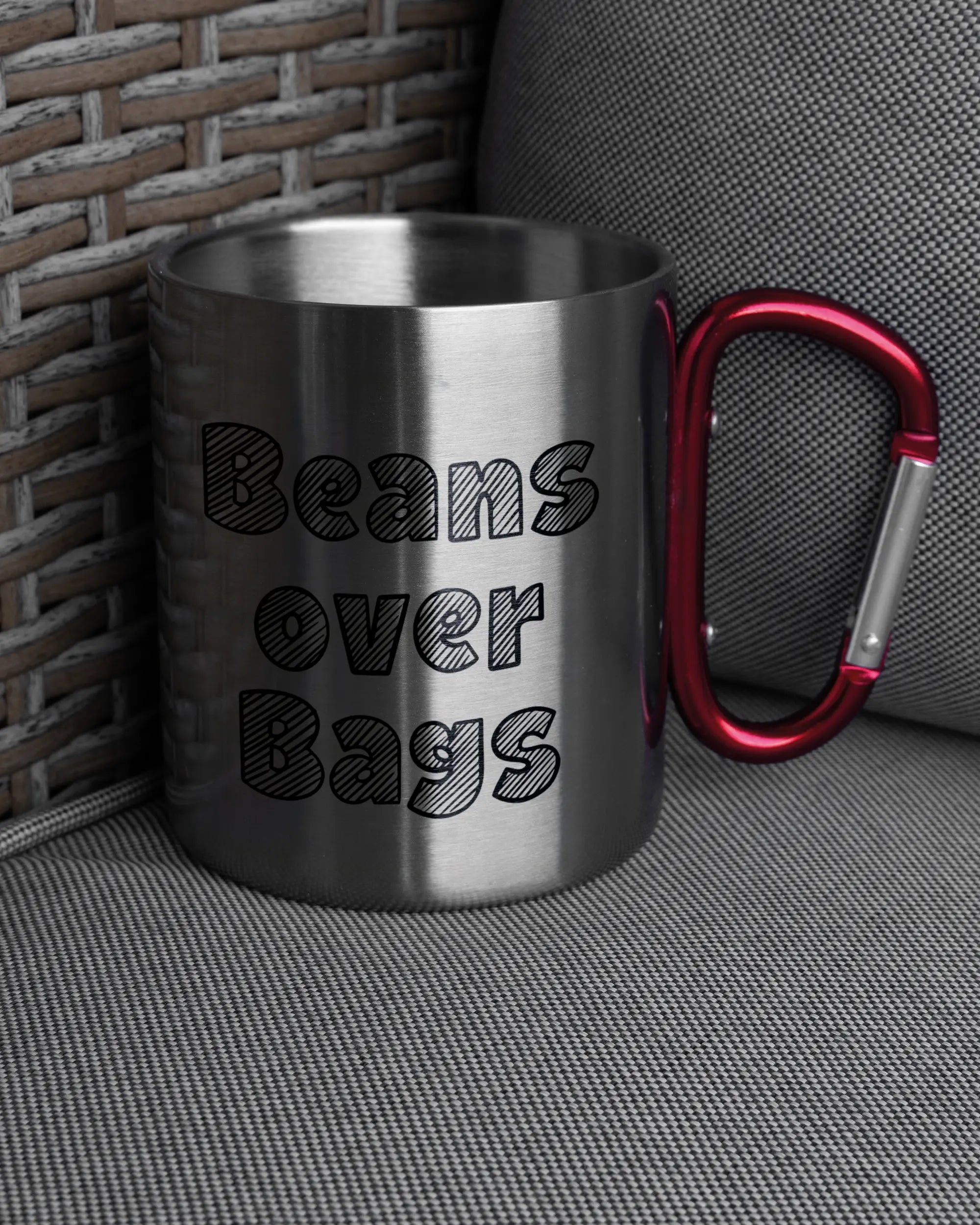 Ansicht der rechten Seite der beidseitig bedruckten Edelstahltasse von Maondo auf einem Balkonmöbel bzw. Campingstuhl mit dem Design Beans over Bags in der Farbe Metallic-Red