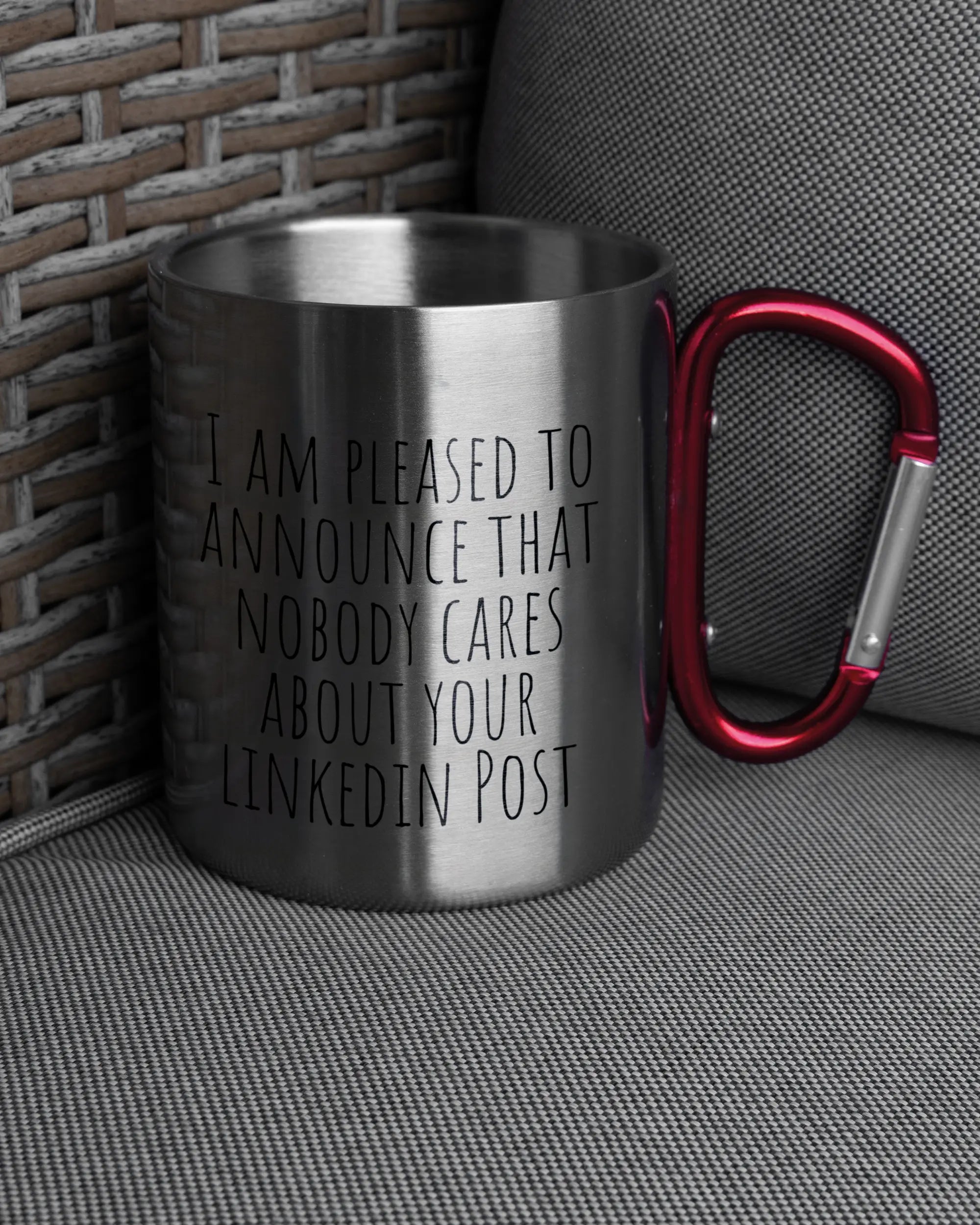 Ansicht der rechten Seite der beidseitig bedruckten Edelstahltasse von Maondo auf einem Balkonmöbel bzw. Campingstuhl mit dem Design Please Unannounce in der Farbe Metallic-Red