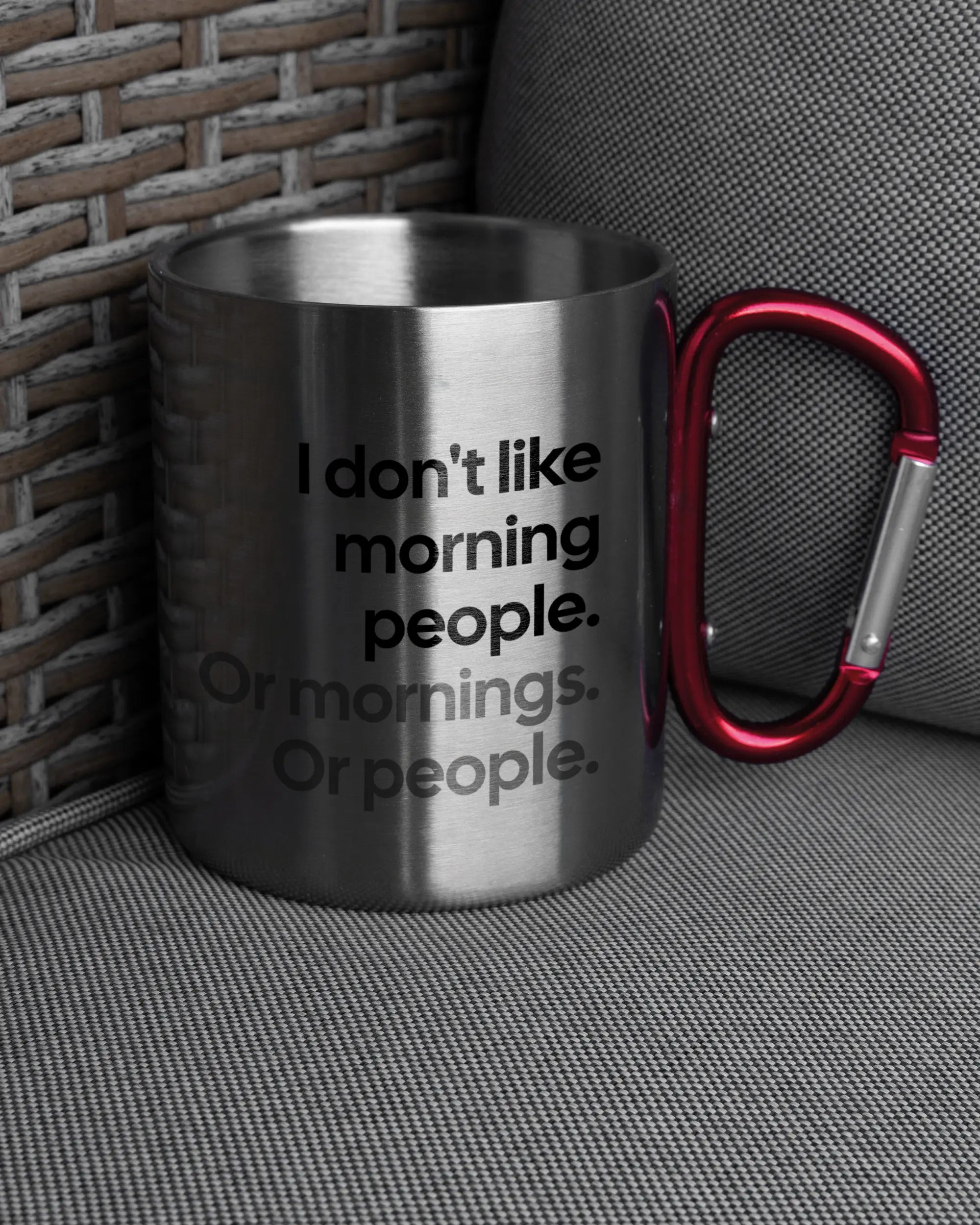 Ansicht der rechten Seite der beidseitig bedruckten Edelstahltasse von Maondo auf einem Balkonmöbel bzw. Campingstuhl mit dem Design Morning Person in der Farbe Metallic-Red