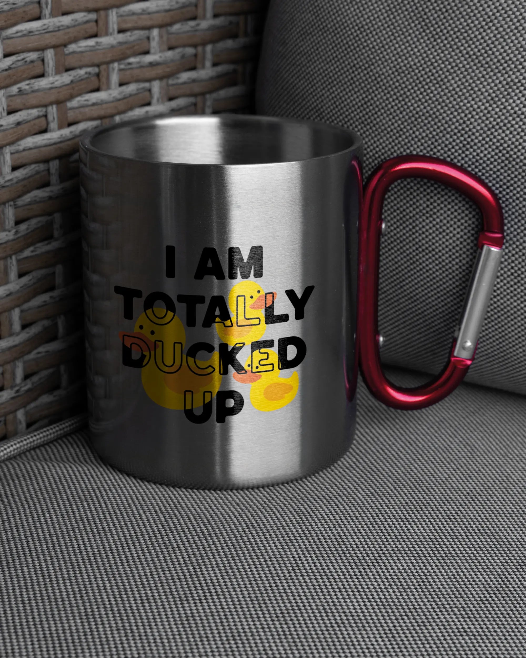 Ansicht der rechten Seite der beidseitig bedruckten Edelstahltasse von Maondo auf einem Balkonmöbel bzw. Campingstuhl mit dem Design Ducked Up in der Farbe Metallic-Red