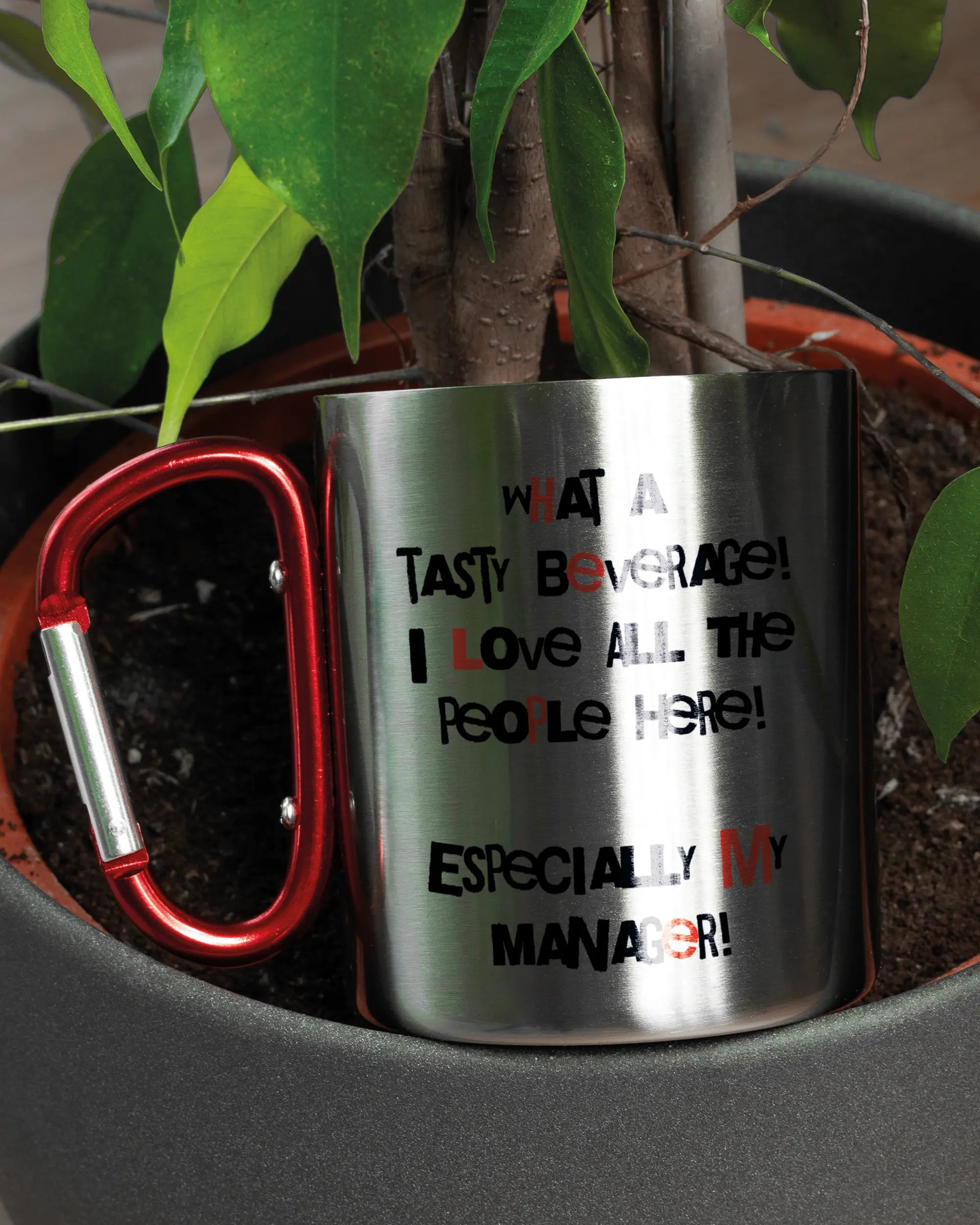 Aufnahme der linken Seite der beidseitig bedruckten Edelstahltasse von Maondo mit dem Design Help me in der Farbe Metallic-Red in einem Blumentopf