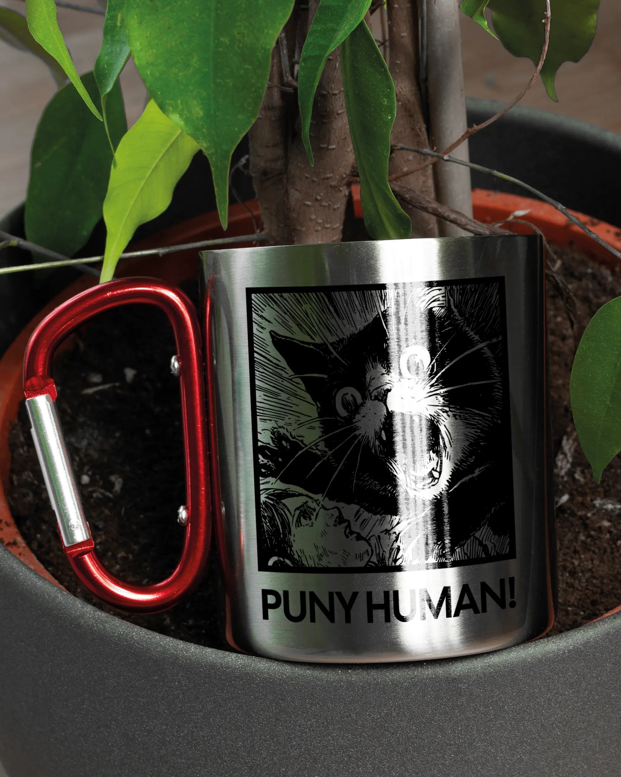 Aufnahme der linken Seite der beidseitig bedruckten Edelstahltasse von Maondo mit dem Design Puny Human in der Farbe Metallic-Red in einem Blumentopf