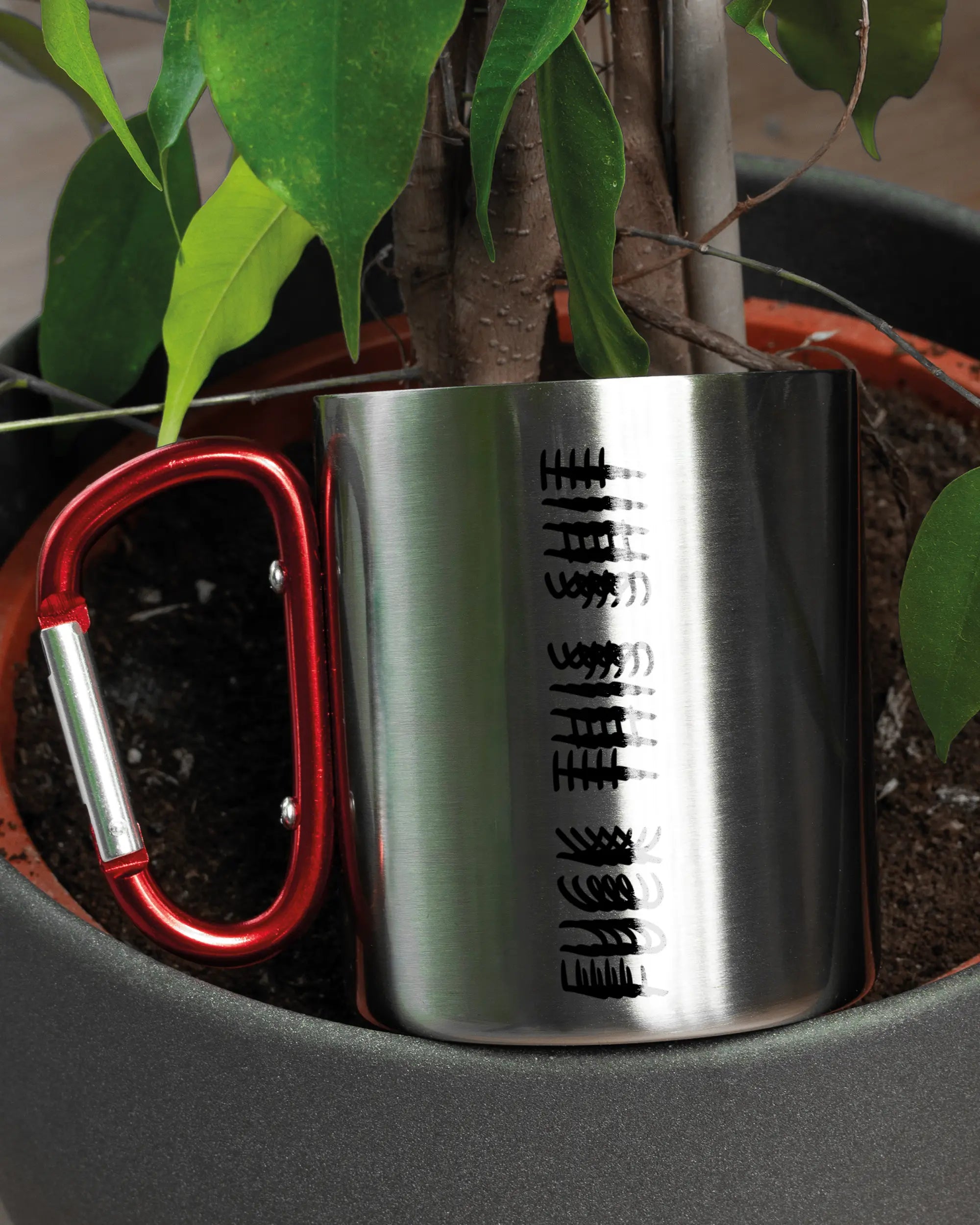 Aufnahme der linken Seite der beidseitig bedruckten Edelstahltasse von Maondo mit dem Design Hidden Message in der Farbe Metallic-Red in einem Blumentopf