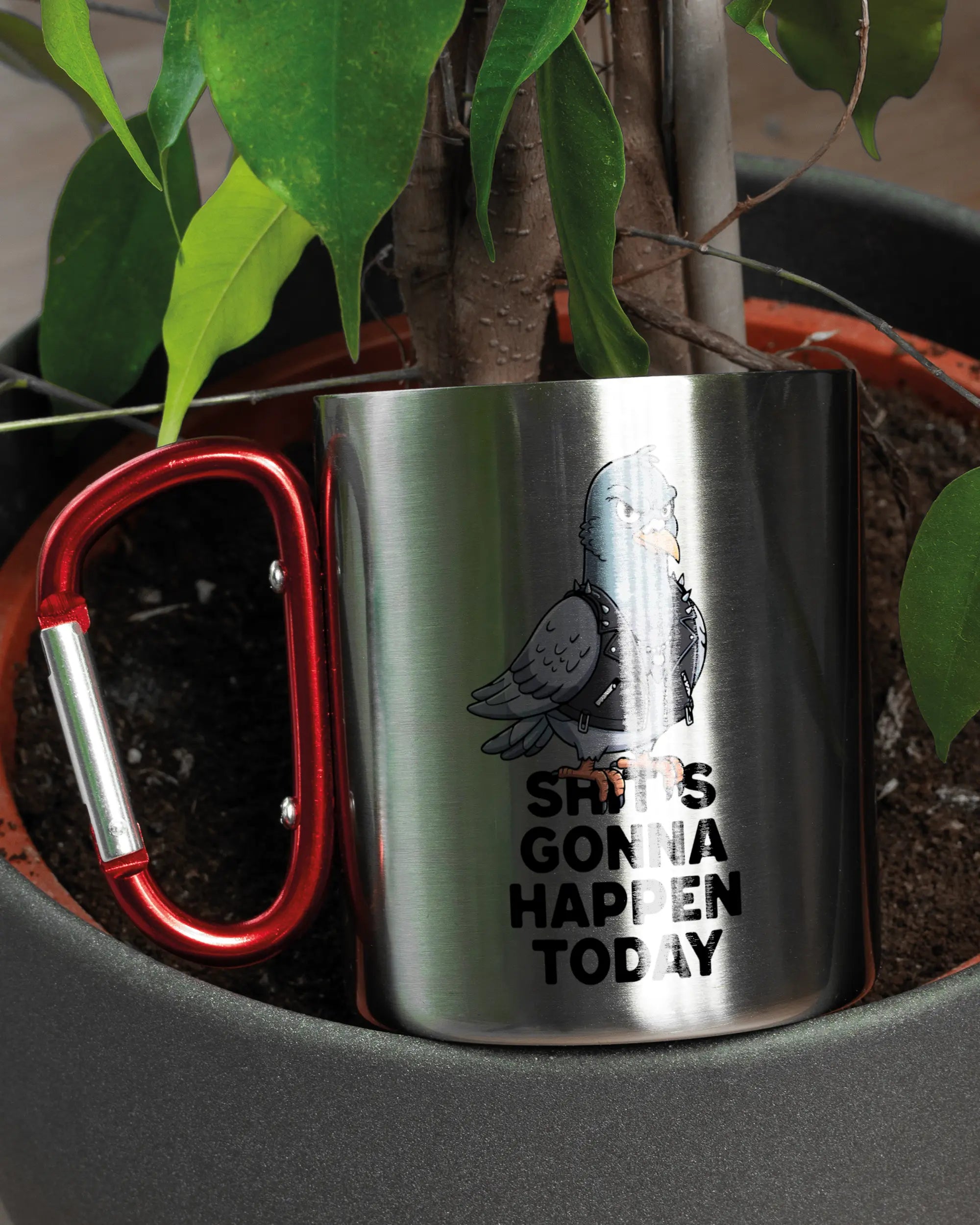 Aufnahme der linken Seite der beidseitig bedruckten Edelstahltasse von Maondo mit dem Design Pigeon Pun in der Farbe Metallic-Red in einem Blumentopf