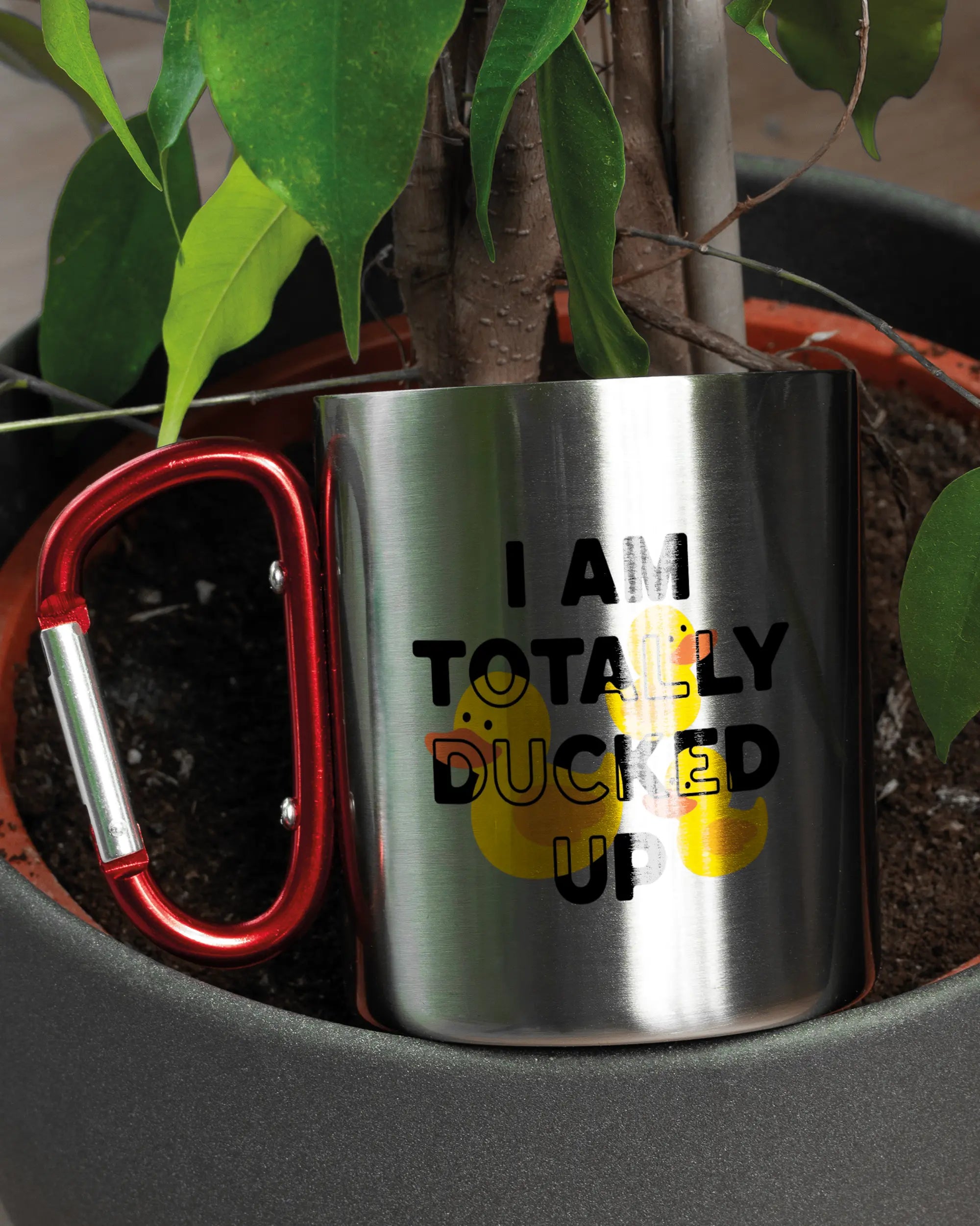 Aufnahme der linken Seite der beidseitig bedruckten Edelstahltasse von Maondo mit dem Design Ducked Up in der Farbe Metallic-Red in einem Blumentopf