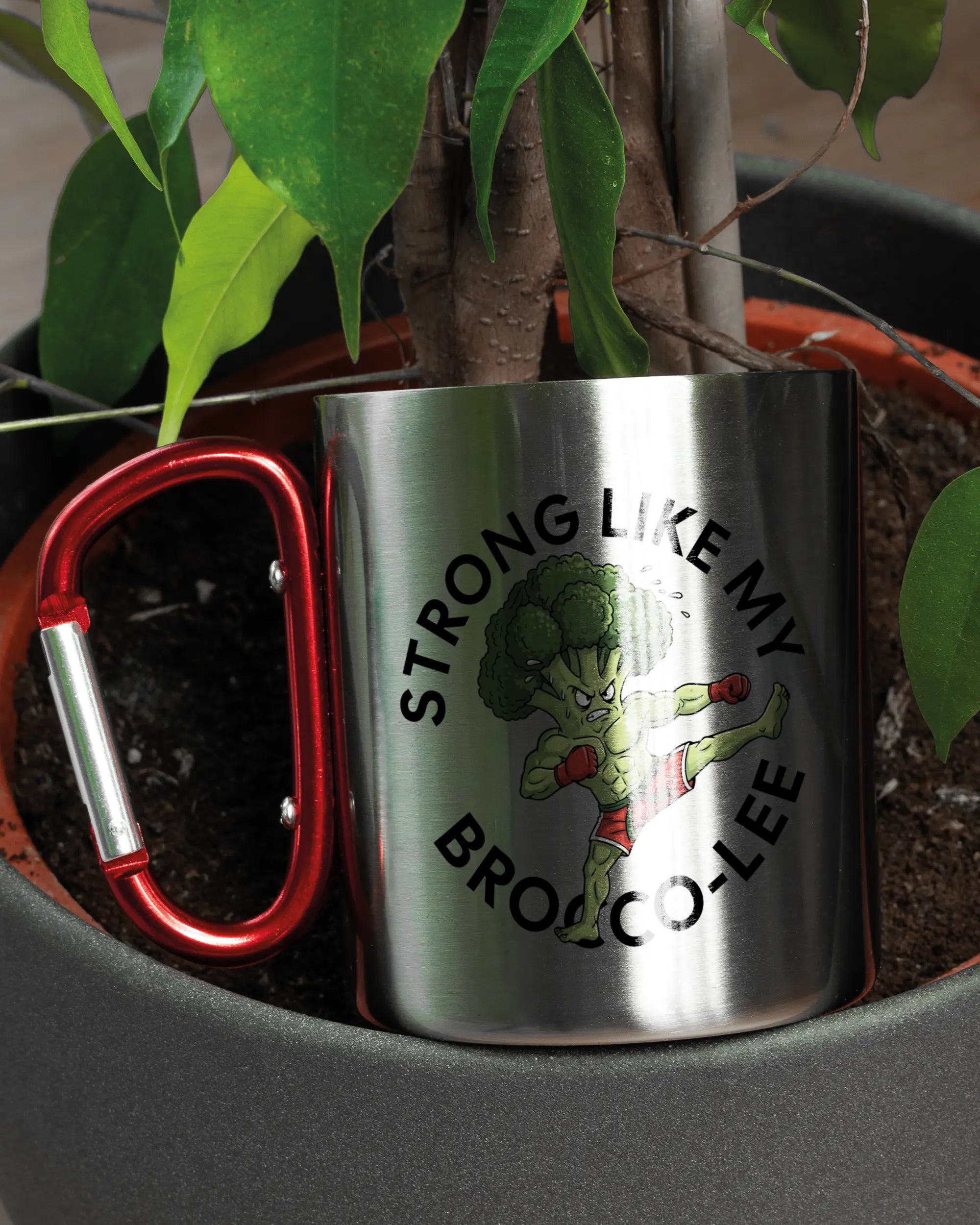 Aufnahme der linken Seite der beidseitig bedruckten Edelstahltasse von Maondo mit dem Design Brocco-Lee in der Farbe Metallic-Red in einem Blumentopf