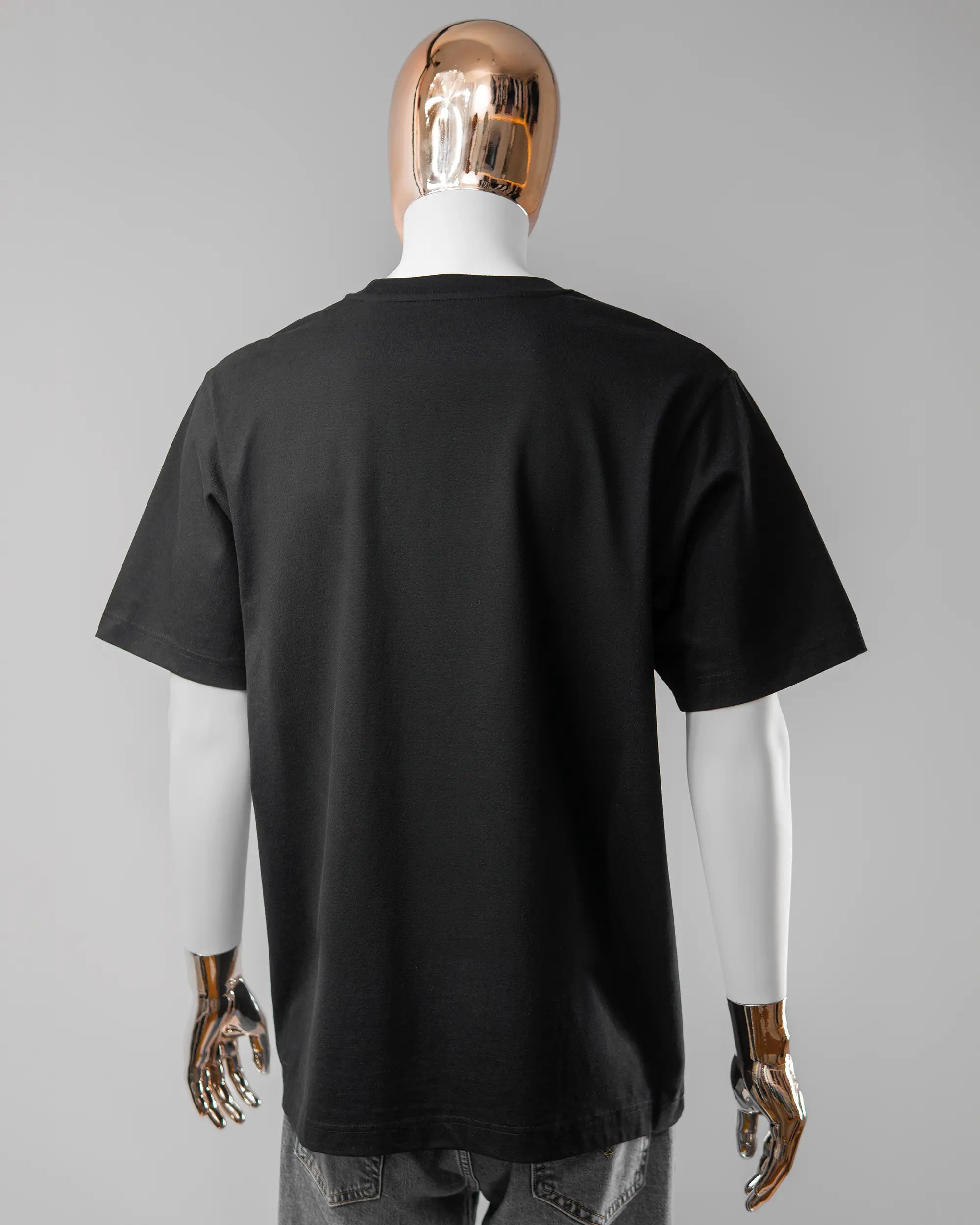 Rückseite des Organic Unisex T-Shirt Heavy Oversized von Maondo ohne Motiv in der Farbe Black und in der Größe L getragen von einer maskulinen Puppe