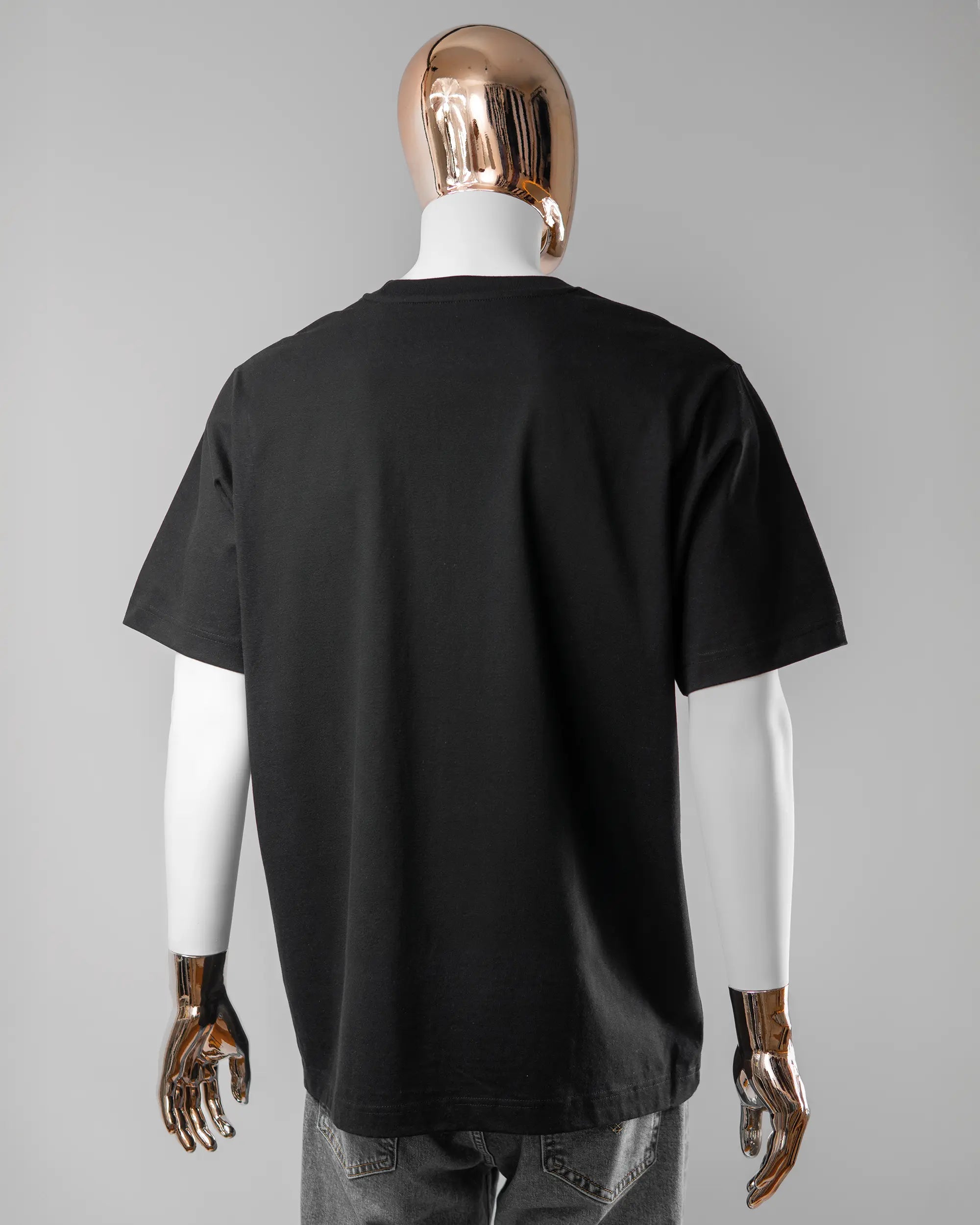 Rückseite des Organic Unisex T-Shirt Heavy Oversized von Maondo ohne Motiv in der Farbe Black und in der Größe L getragen von einer maskulinen Puppe