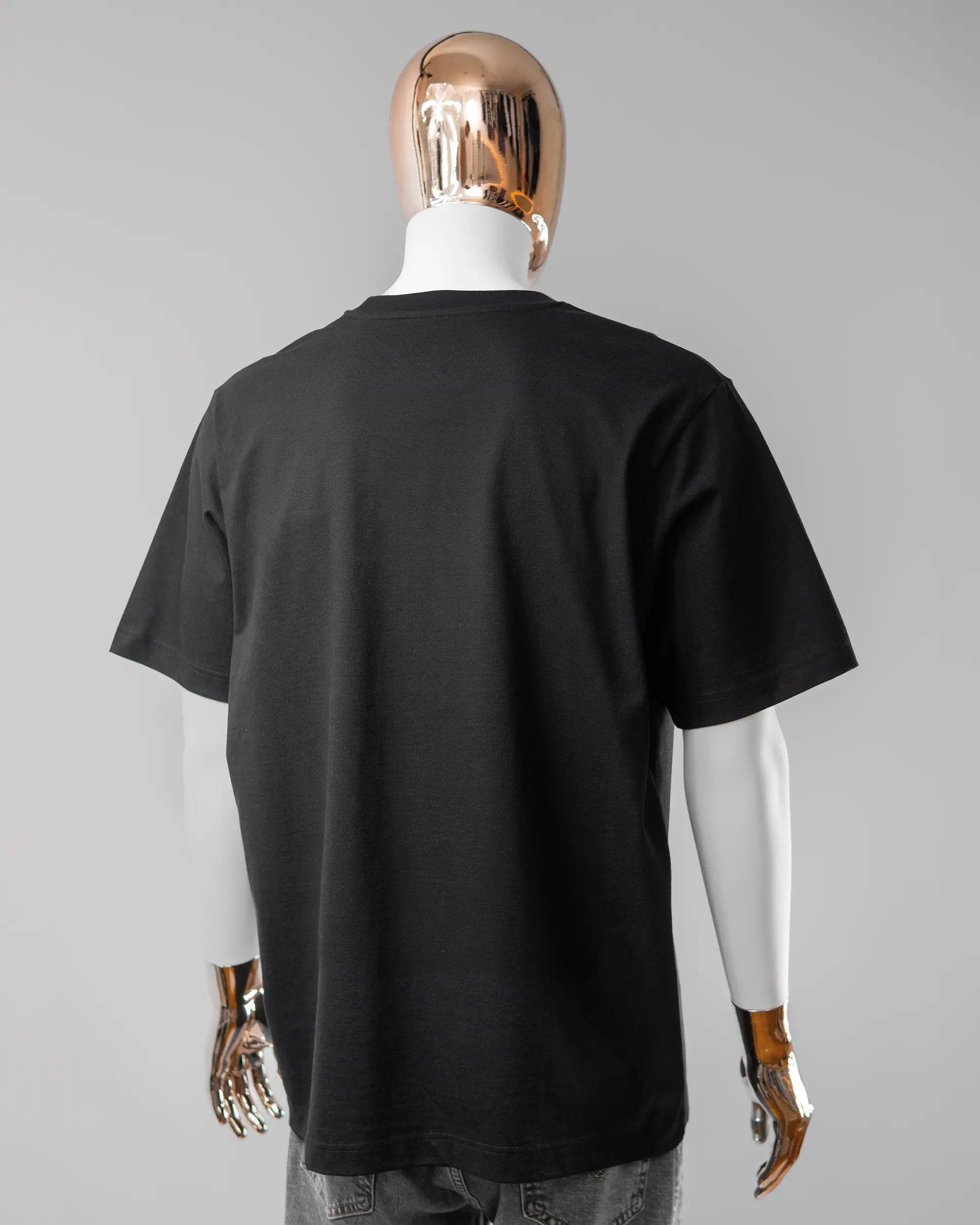 Rückseite des Organic Unisex T-Shirt Heavy Oversized von Maondo ohne Motiv in der Farbe Black und in der Größe L getragen von einer maskulinen Puppe