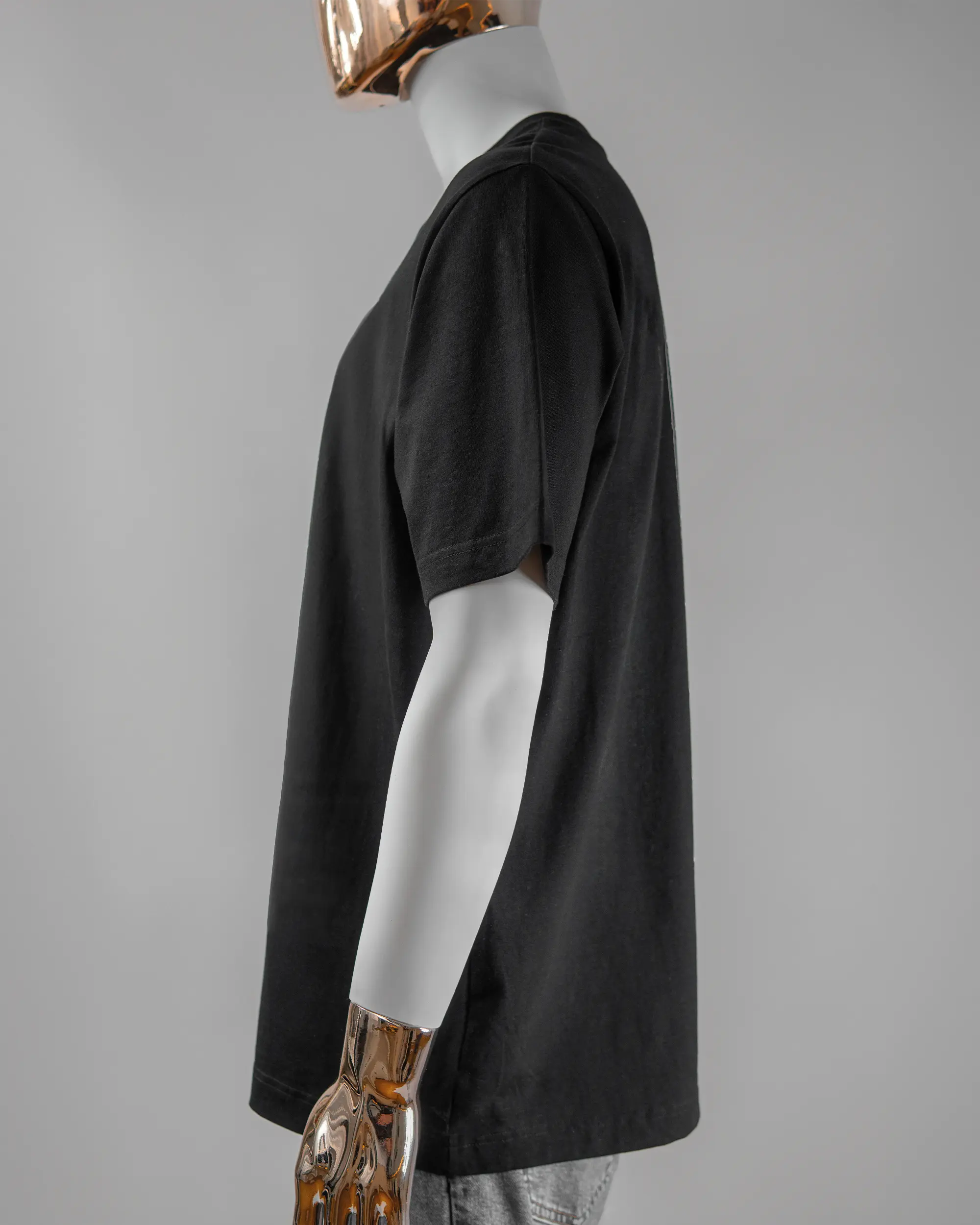 Seitenansicht des Organic Unisex T-Shirt Heavy Oversized von Maondo mit dem Design Pigeon Pun vorne in der Farbe Black und in der Größe L getragen von einer maskulinen Puppe