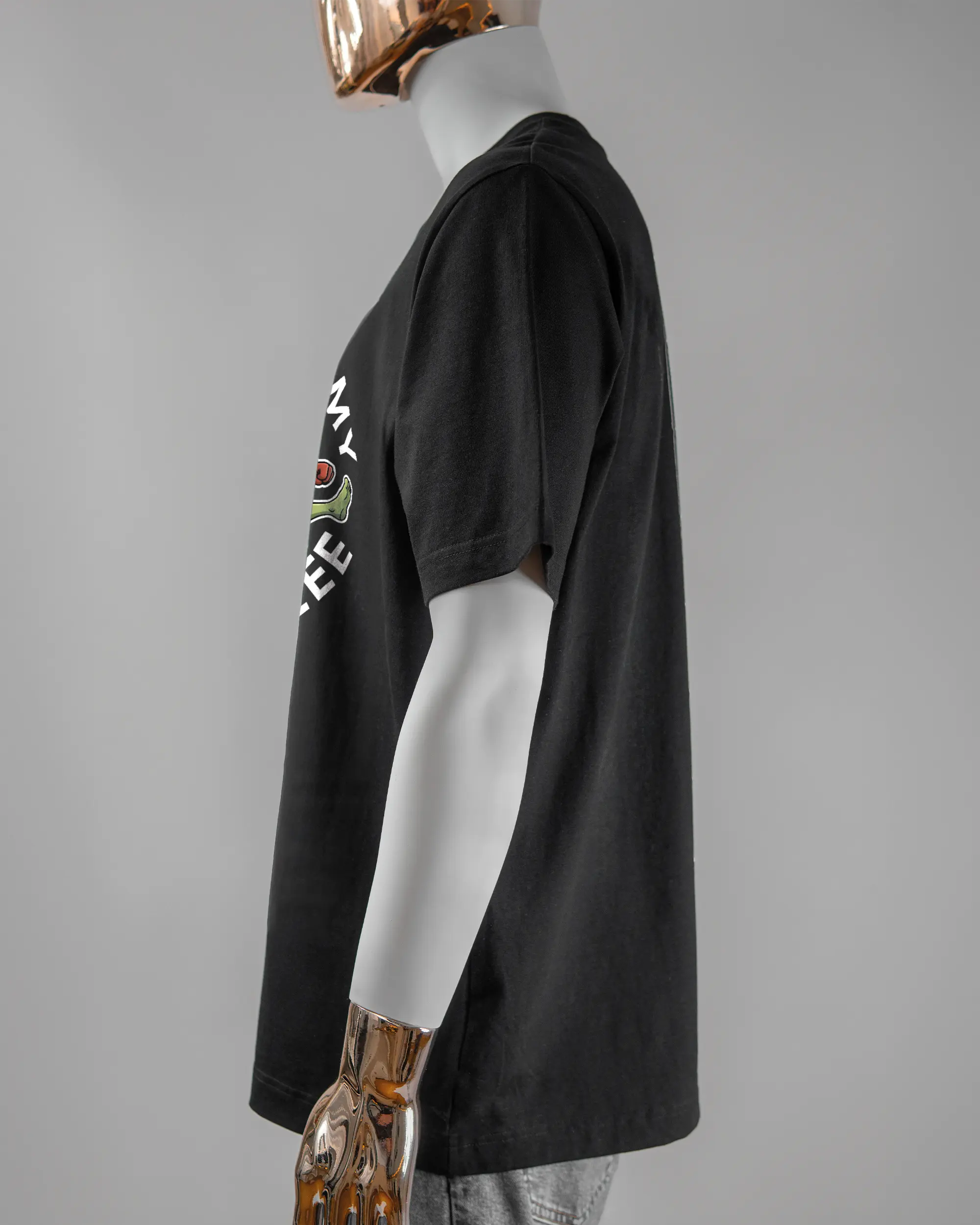 Seitenansicht des Organic Unisex T-Shirt Heavy Oversized von Maondo mit dem Design Brocco-Lee vorne in der Farbe Black und in der Größe L getragen von einer maskulinen Puppe