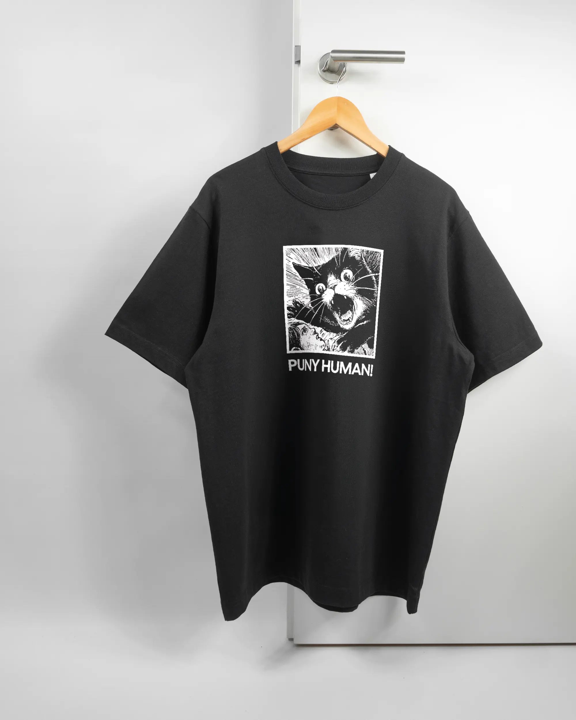 Vorderseite des Organic Unisex T-Shirt Heavy Oversized von Maondo mit dem Design Puny Human in der Farbe Black und in der Größe L auf einem Bügel an der Türklinke aufgehängt