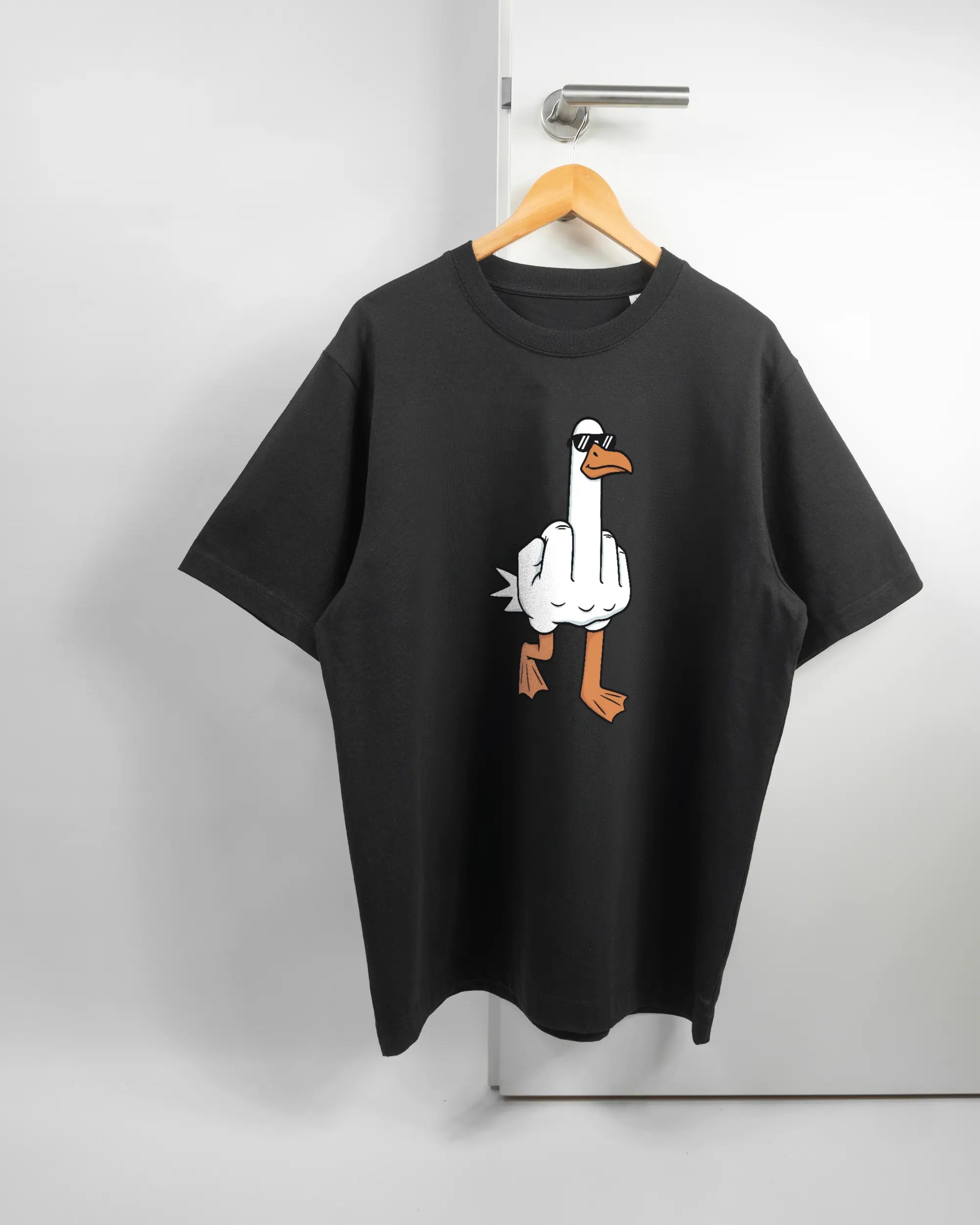 Vorderseite des Organic Unisex T-Shirt Heavy Oversized von Maondo mit dem Design I give a duck in der Farbe Black und in der Größe L auf einem Bügel an der Türklinke aufgehängt