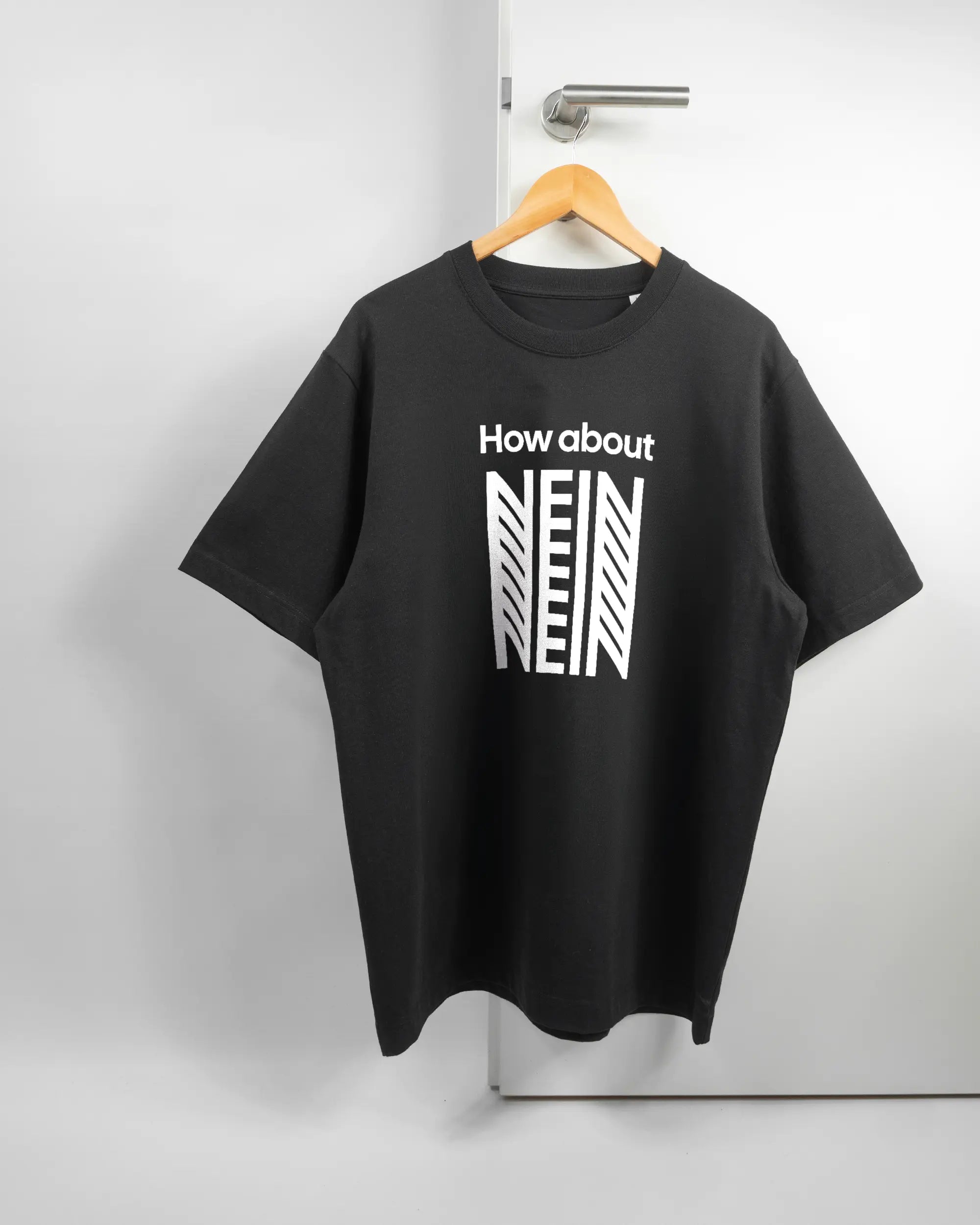 Vorderseite des Organic Unisex T-Shirt Heavy Oversized von Maondo mit dem Design How about nein in der Farbe Black und in der Größe L auf einem Bügel an der Türklinke aufgehängt
