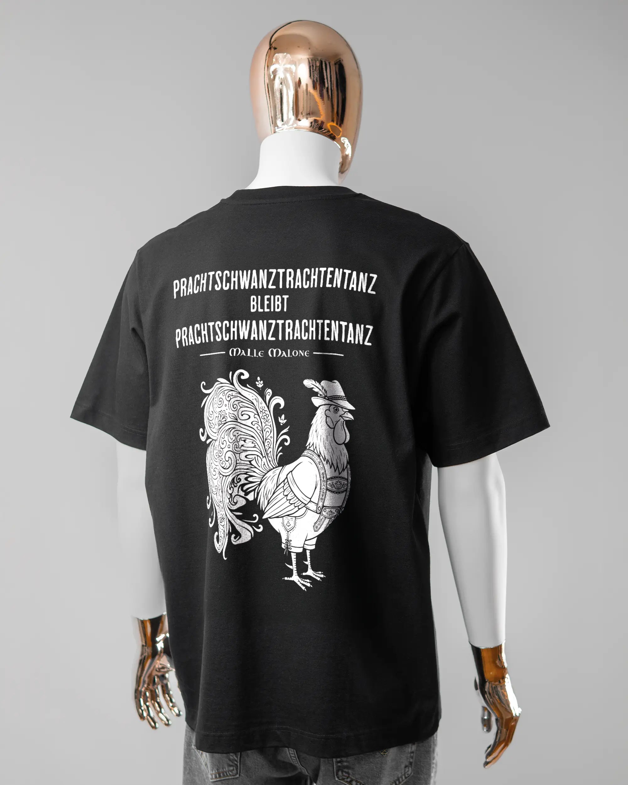 Rückseite des Organic Unisex T-Shirt Heavy Oversized von Maondo mit dem Design Trachtentanz in der Farbe Black und in der Größe L getragen von einer maskulinen Puppe