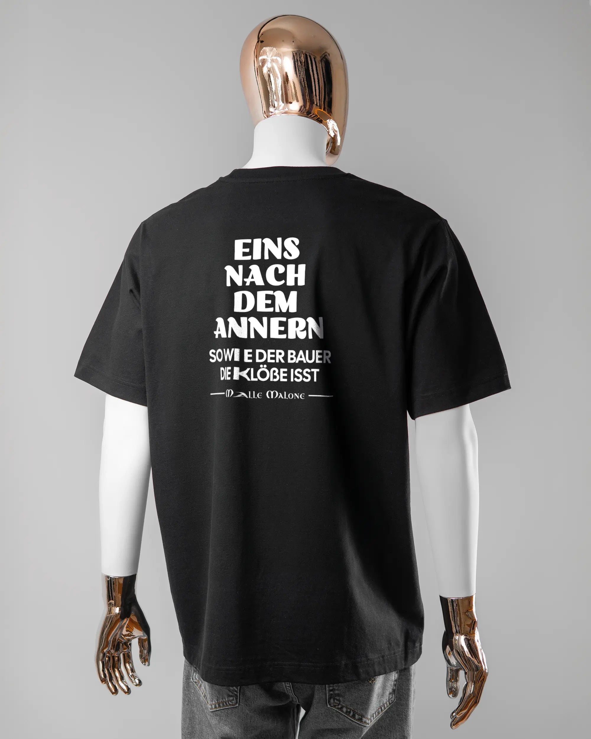 Rückseite des Organic Unisex T-Shirt Heavy Oversized von Maondo mit dem Design Eins nach dem Annern in der Farbe Black und in der Größe L getragen von einer maskulinen Puppe
