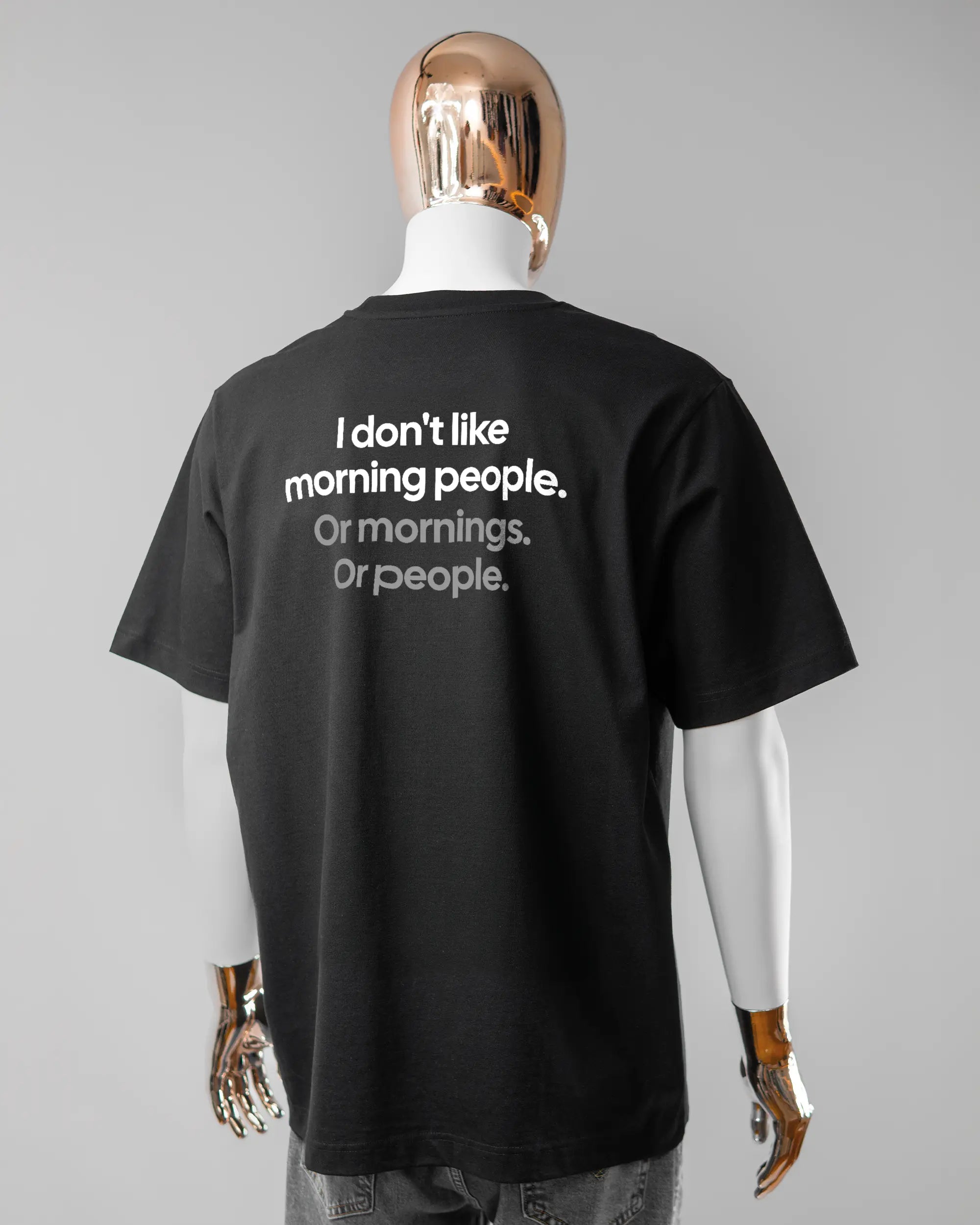 Rückseite des Organic Unisex T-Shirt Heavy Oversized von Maondo mit dem Design Morning Person in der Farbe Black und in der Größe L getragen von einer maskulinen Puppe