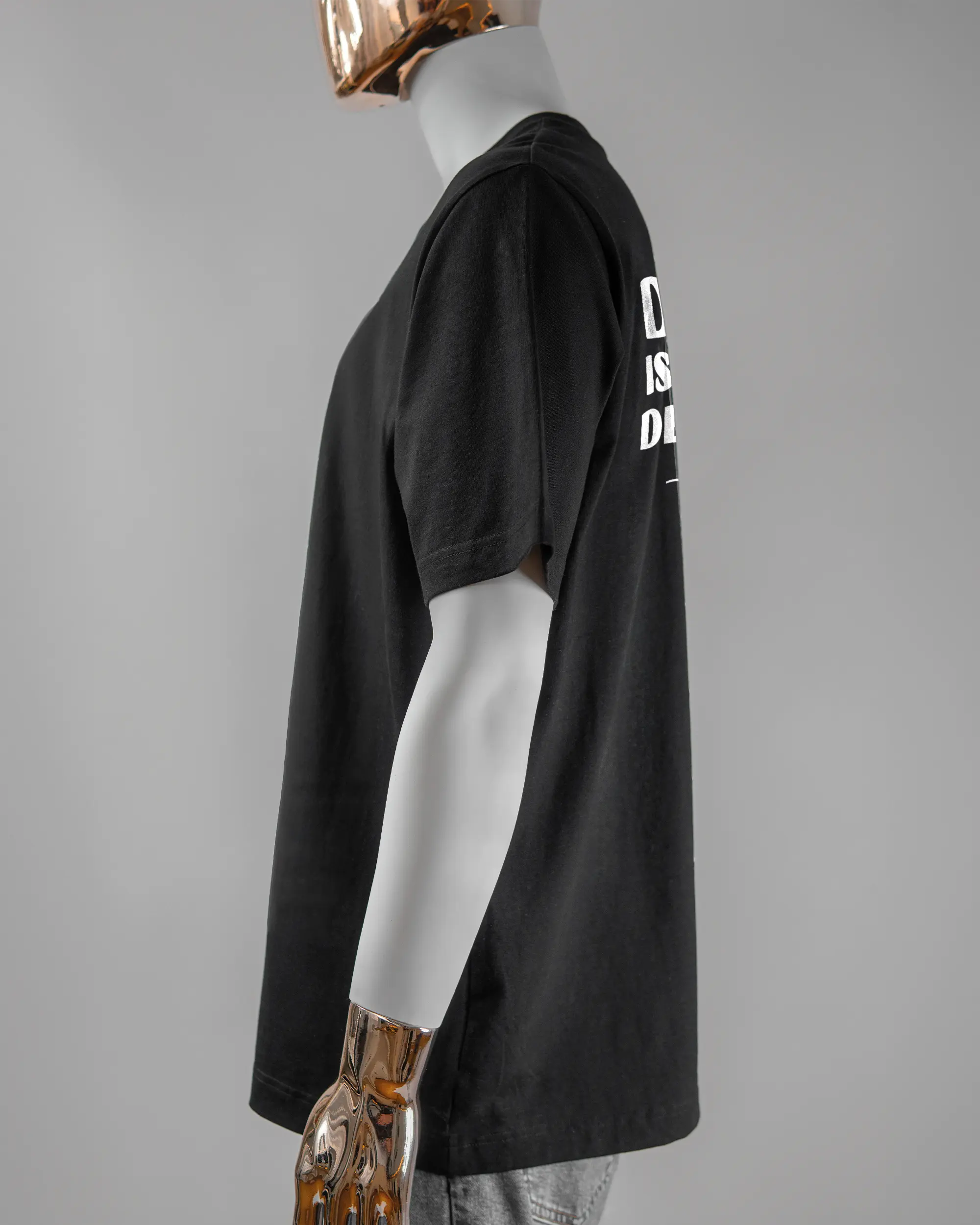 Seitenansicht des Organic Unisex T-Shirt Heavy Oversized von Maondo mit dem Design Keine Eile hinten in der Farbe Black und in der Größe L getragen von einer maskulinen Puppe