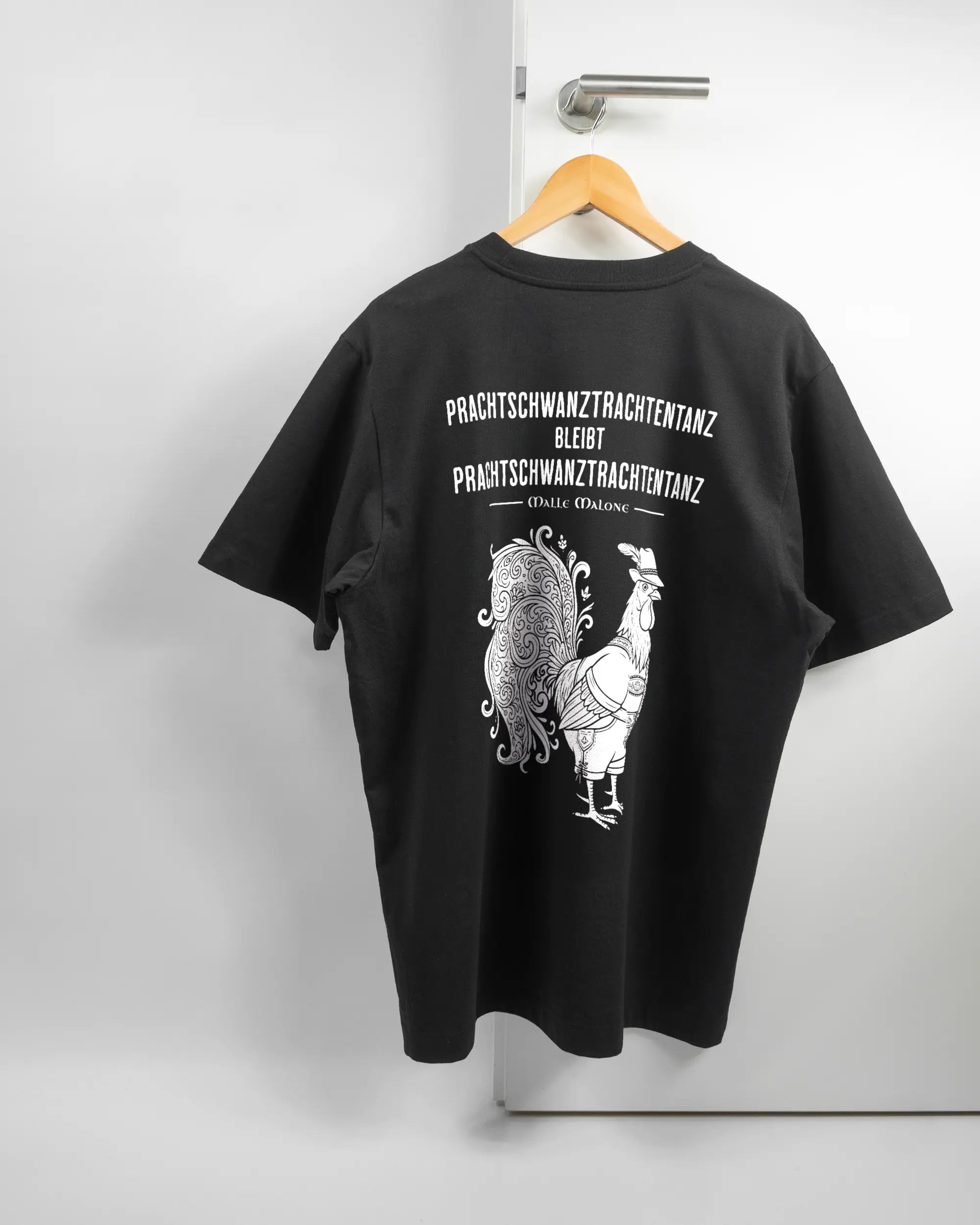 Rückseite des Organic Unisex T-Shirt Heavy Oversized von Maondo mit dem Design Trachtentanz in der Farbe Black und in der Größe L auf einem Bügel an der Türklinke aufgehängt