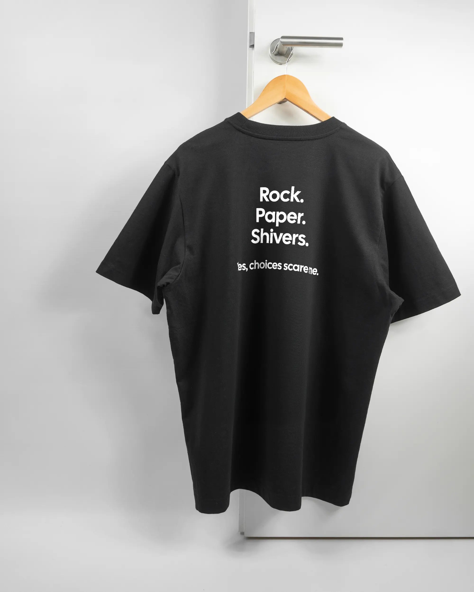 Rückseite des Organic Unisex T-Shirt Heavy Oversized von Maondo mit dem Design Rock Paper Shivers in der Farbe Black und in der Größe L auf einem Bügel an der Türklinke aufgehängt