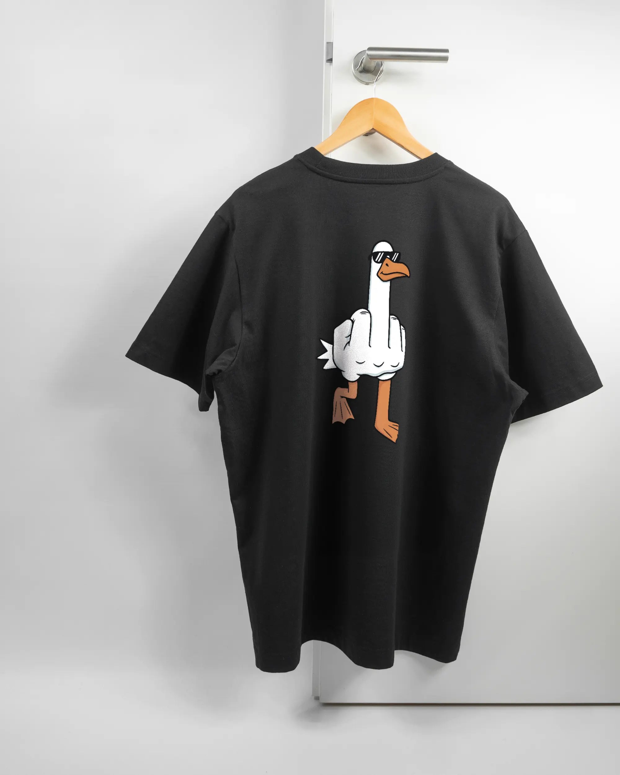 Rückseite des Organic Unisex T-Shirt Heavy Oversized von Maondo mit dem Design I give a duck in der Farbe Black und in der Größe L auf einem Bügel an der Türklinke aufgehängt