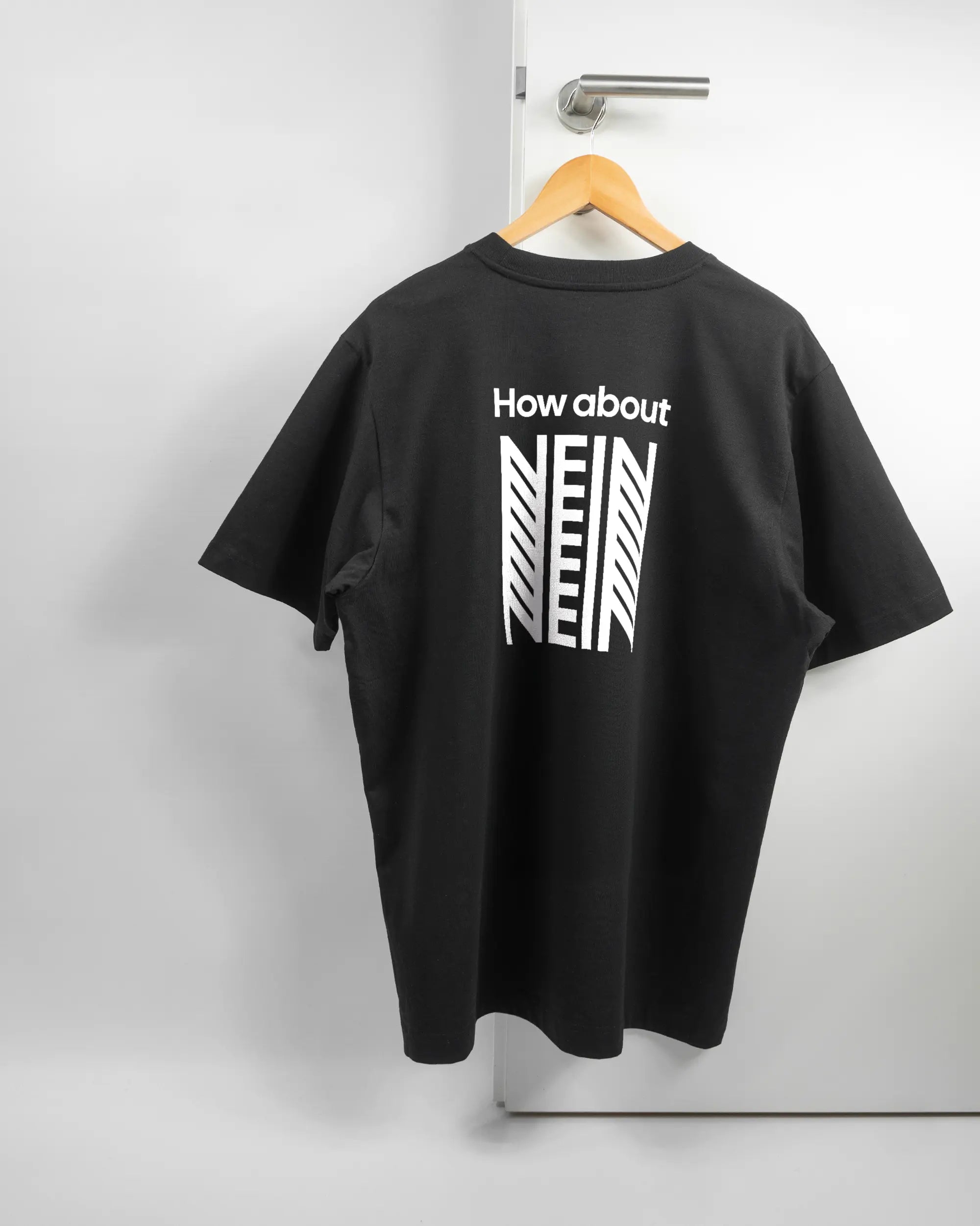 Rückseite des Organic Unisex T-Shirt Heavy Oversized von Maondo mit dem Design How about nein in der Farbe Black und in der Größe L auf einem Bügel an der Türklinke aufgehängt
