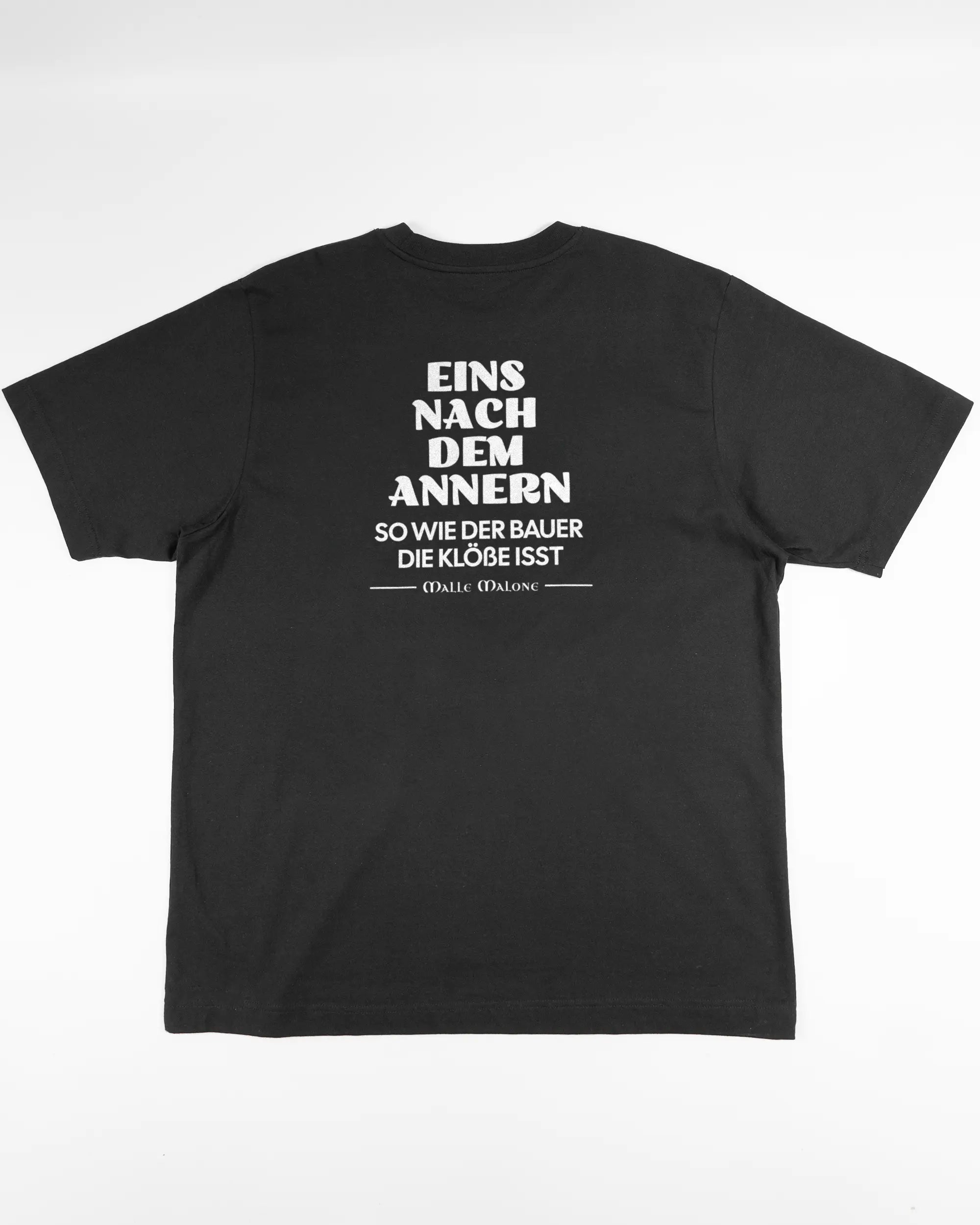Rückseite des Organic Unisex T-Shirt Heavy Oversized von Maondo mit dem Design Eins nach dem Annern in der Farbe Black und in der Größe L flach auf den Boden gelegt