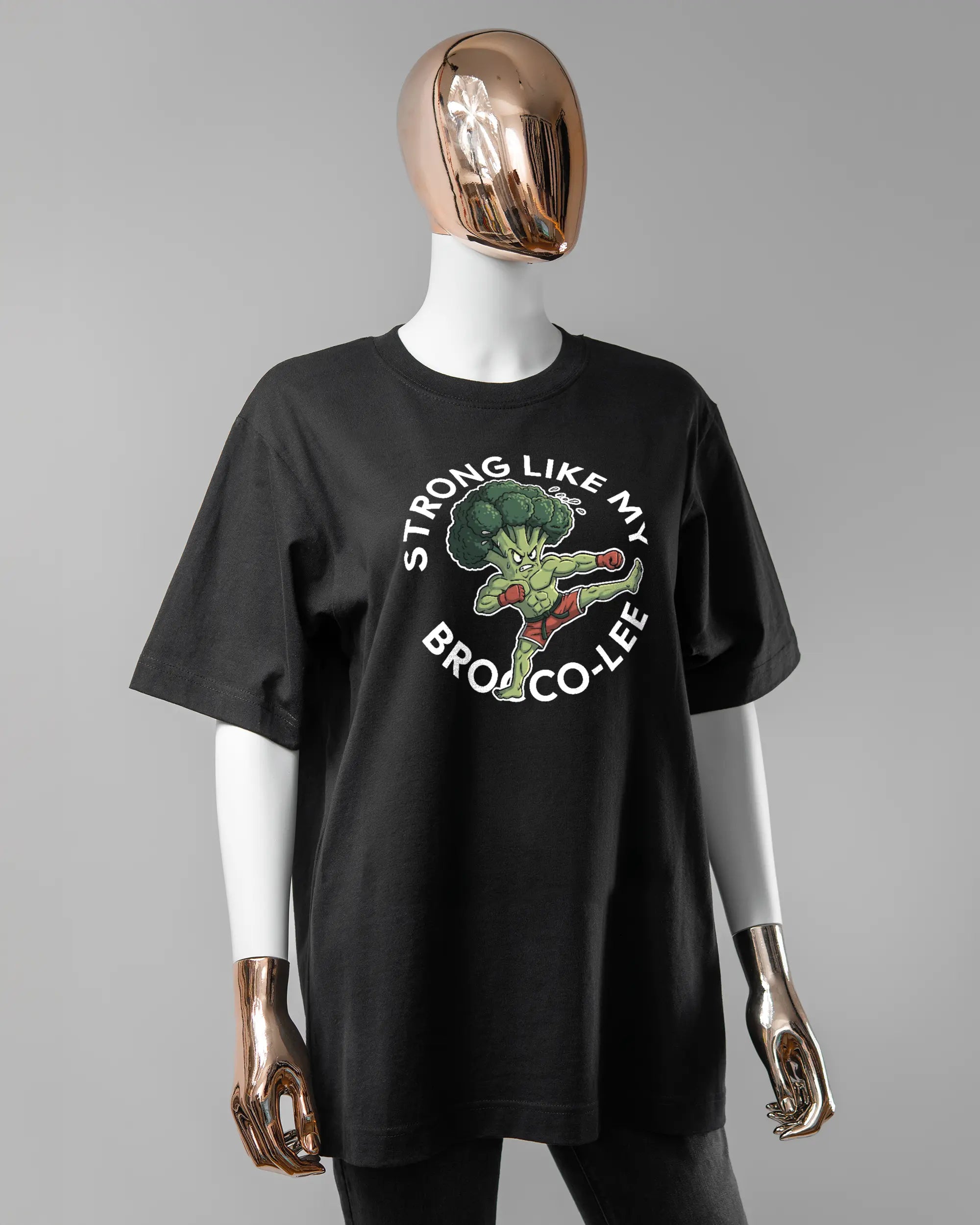 Vorderseite des Organic Unisex T-Shirt Heavy Oversized von Maondo mit dem Design Brocco-Lee in der Farbe Black und in der Größe S getragen von einer femininen Puppe