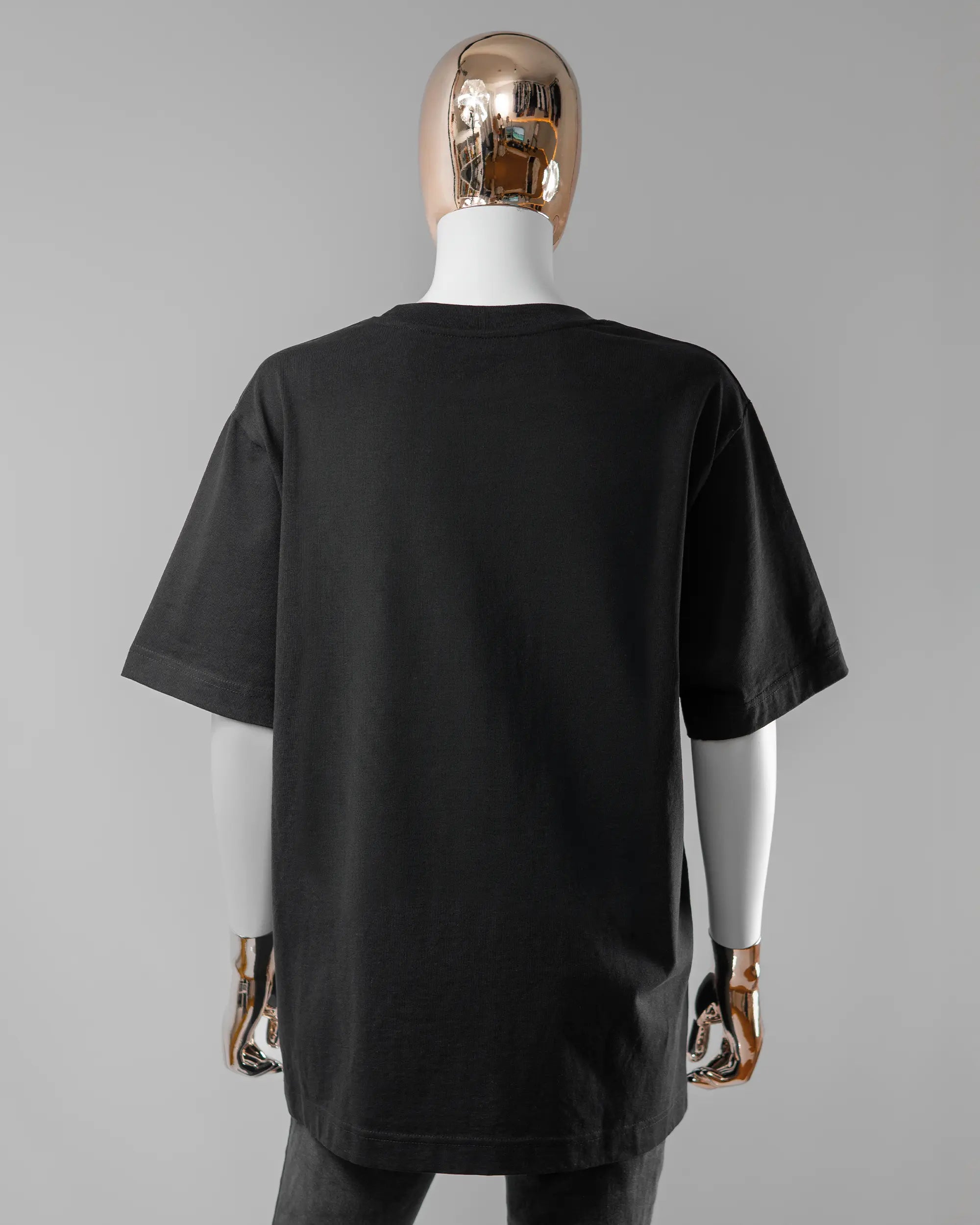 Rückseite des Organic Unisex T-Shirt Heavy Oversized von Maondo ohne Motiv in der Farbe Black und in der Größe S getragen von einer femininen Puppe