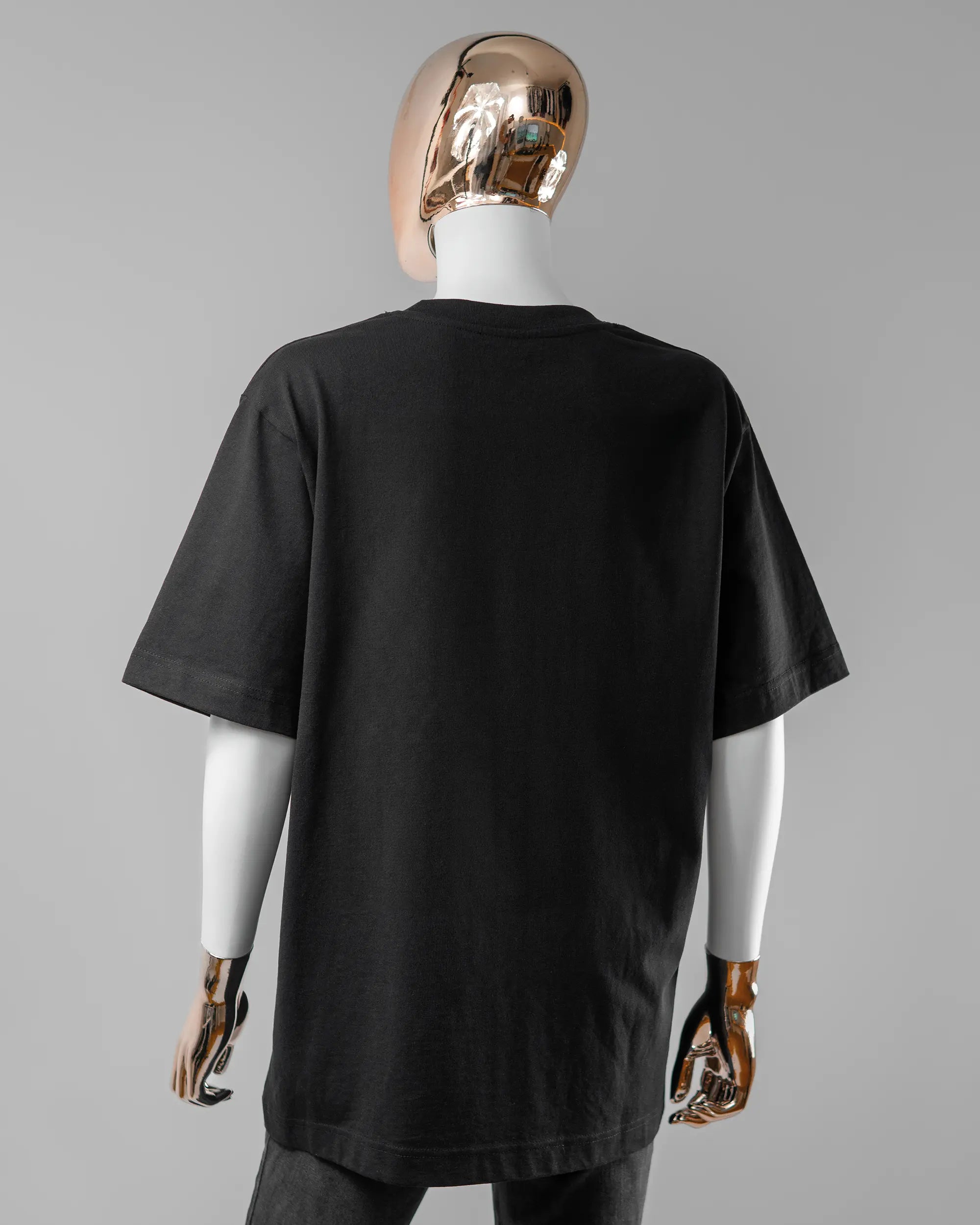 Rückseite des Organic Unisex T-Shirt Heavy Oversized von Maondo ohne Motiv in der Farbe Black und in der Größe S getragen von einer femininen Puppe