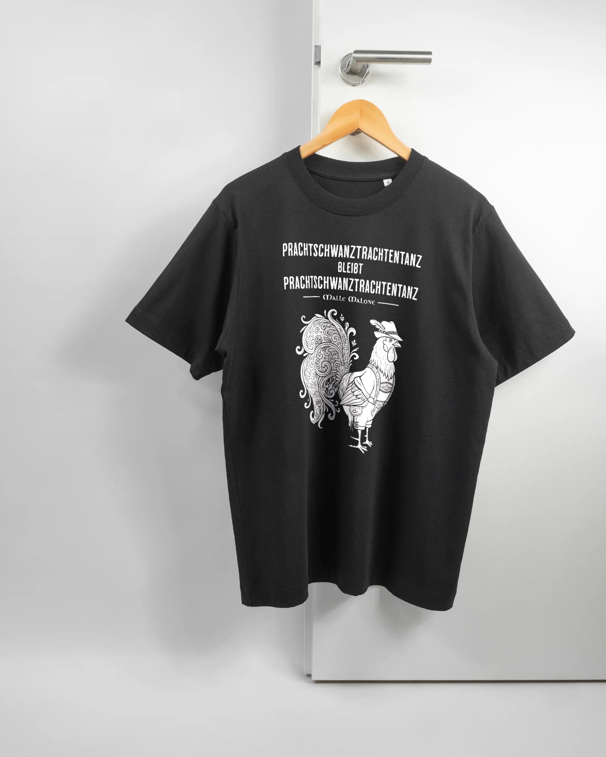 Vorderseite des Organic Unisex T-Shirt Heavy Oversized von Maondo mit dem Design Trachtentanz in der Farbe Black und in der Größe S auf einem Bügel an der Türklinke aufgehängt