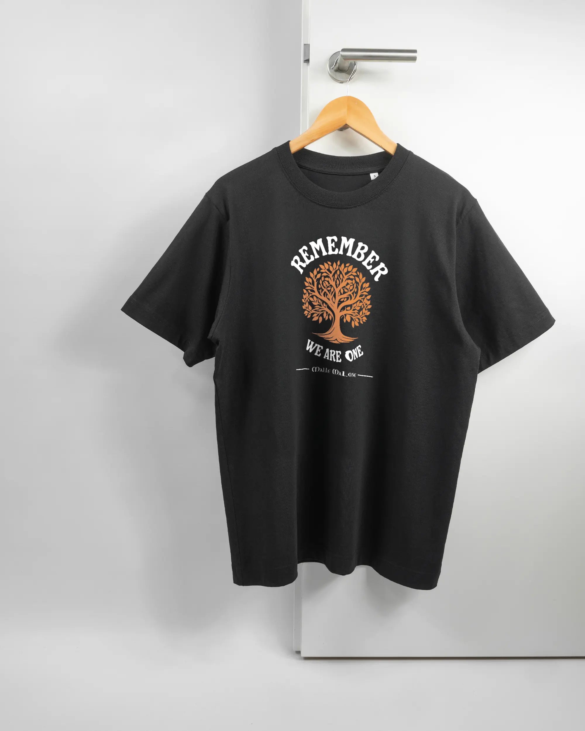 Vorderseite des Organic Unisex T-Shirt Heavy Oversized von Maondo mit dem Design We are one in der Farbe Black und in der Größe S auf einem Bügel an der Türklinke aufgehängt