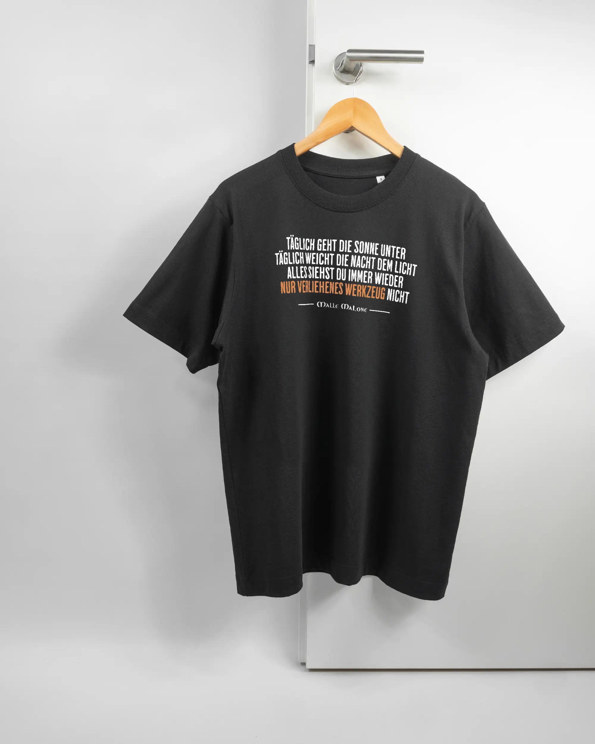 Vorderseite des Organic Unisex T-Shirt Heavy Oversized von Maondo mit dem Design Wegzeug in der Farbe Black und in der Größe S auf einem Bügel an der Türklinke aufgehängt