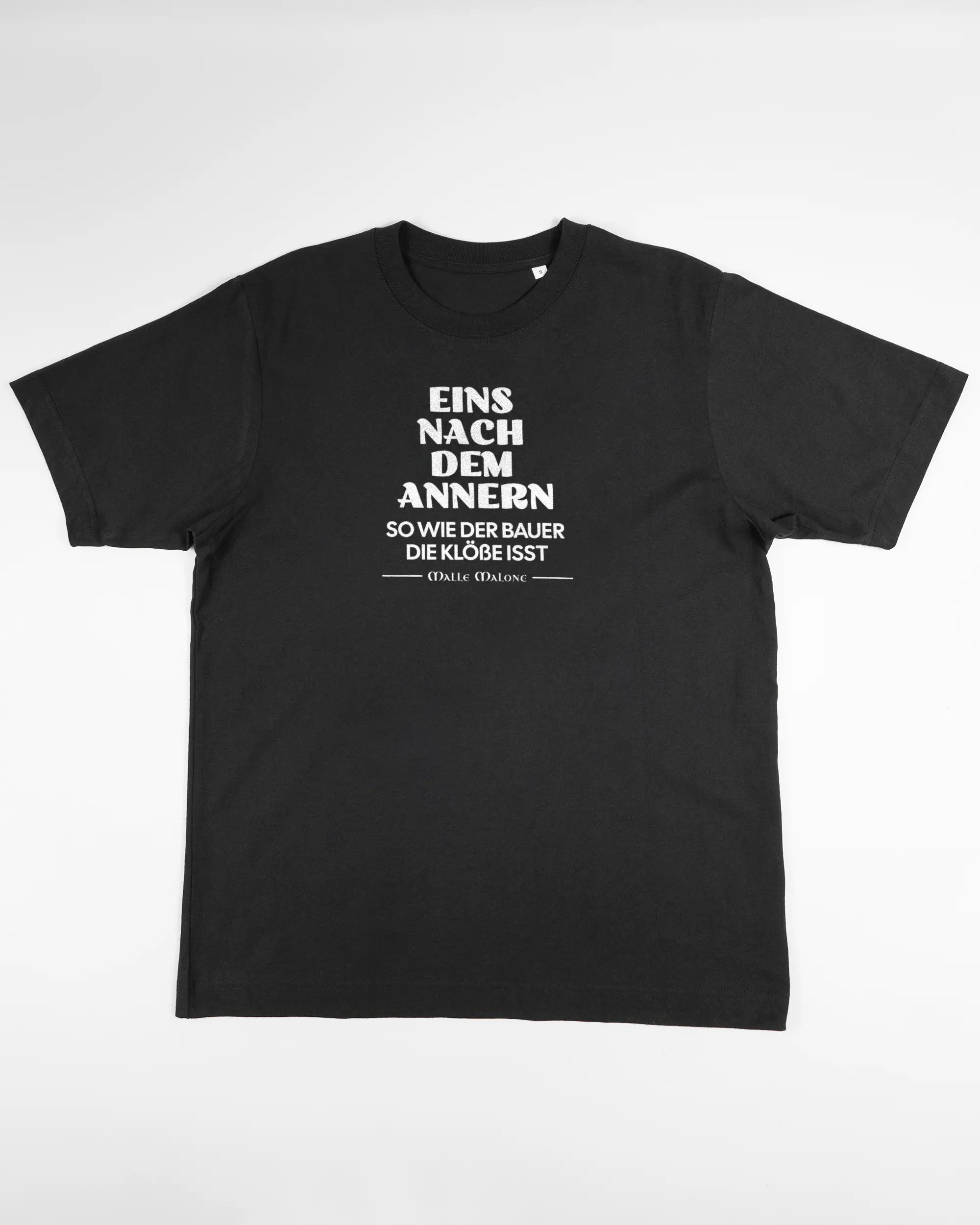 Vorderseite des Organic Unisex T-Shirt Heavy Oversized von Maondo mit dem Design Eins nach dem Annern in der Farbe Black und in der Größe S flach auf den Boden gelegt