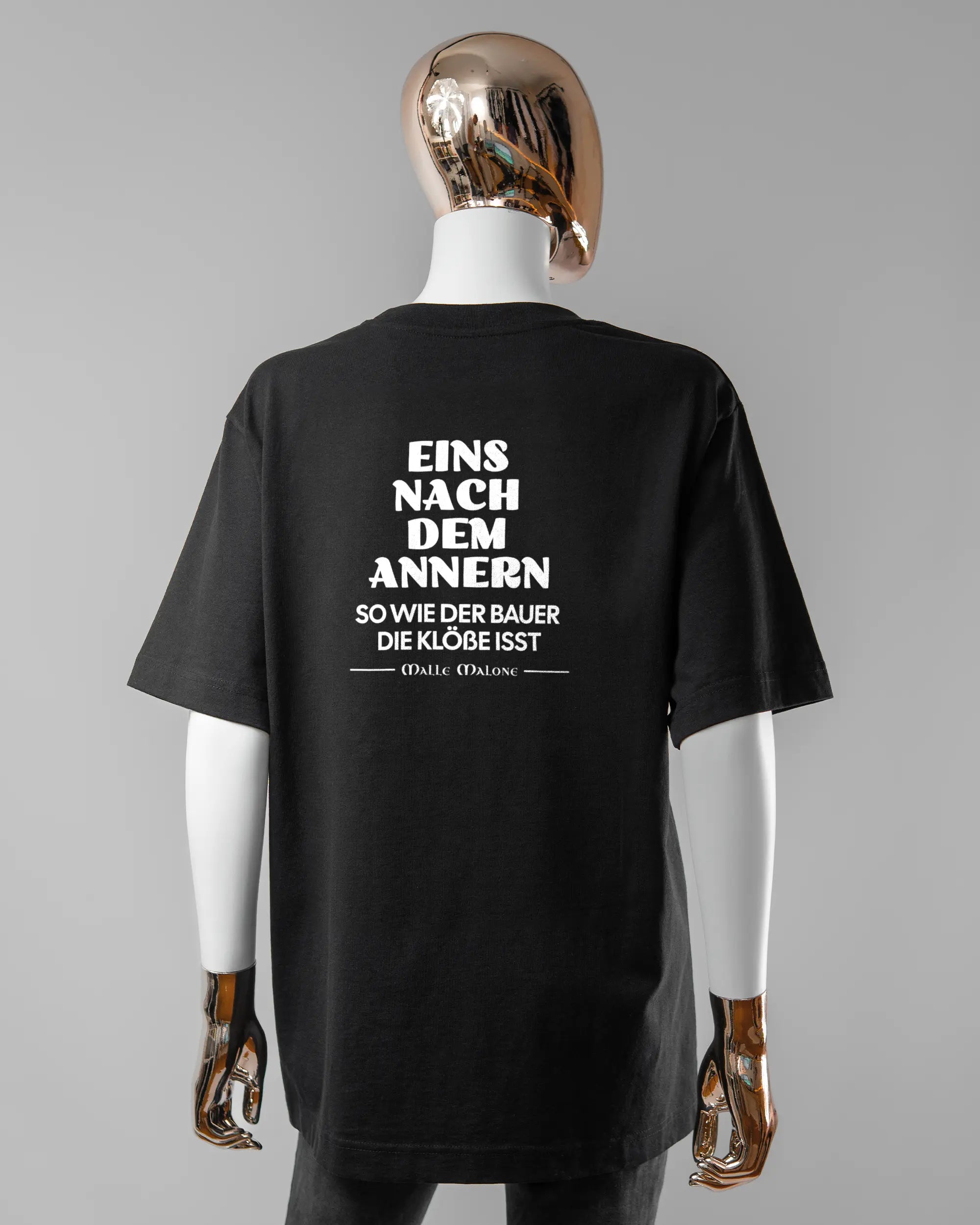 Rückseite des Organic Unisex T-Shirt Heavy Oversized von Maondo mit dem Design Eins nach dem Annern in der Farbe Black und in der Größe S getragen von einer femininen Puppe