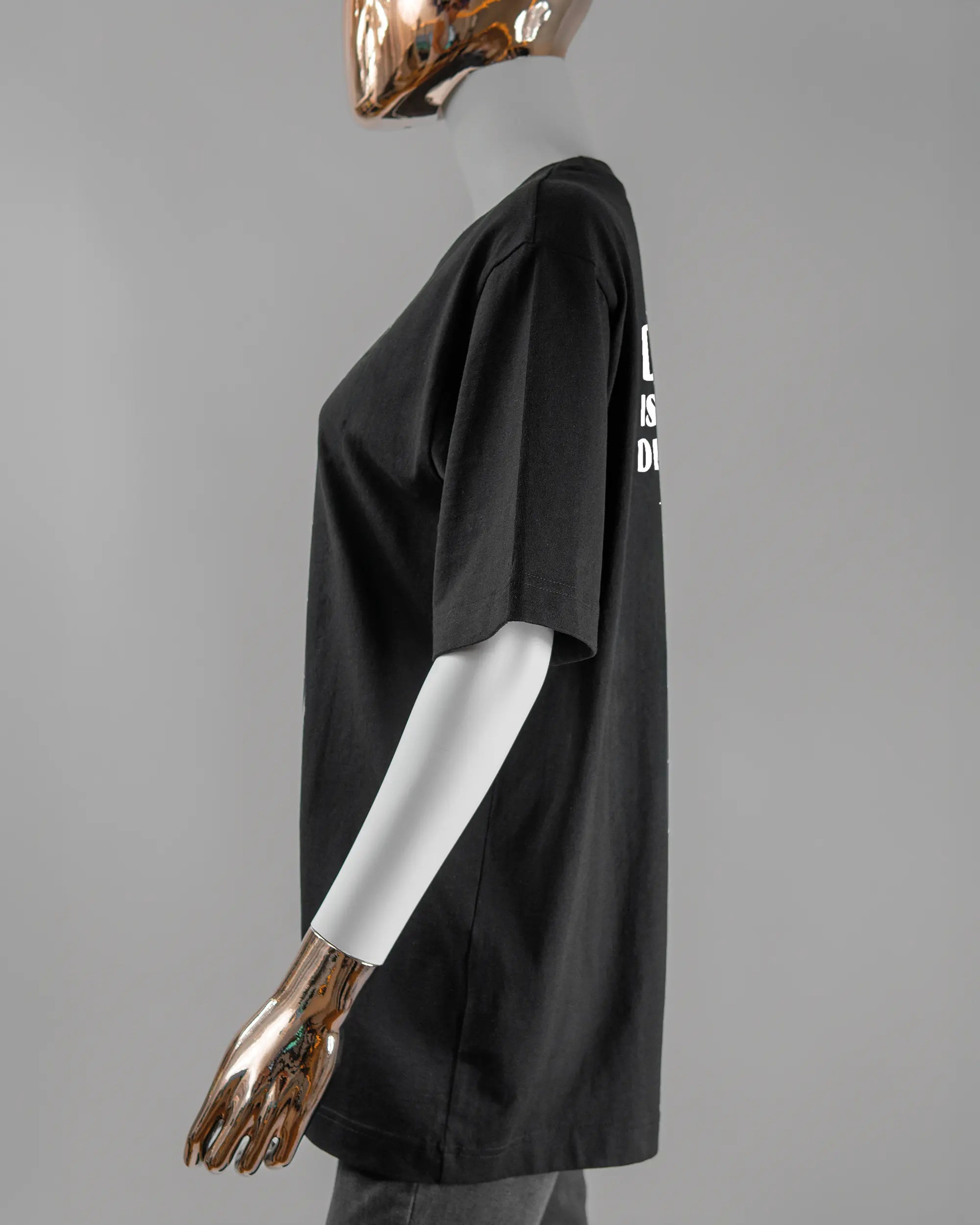 Seitenansicht des Organic Unisex T-Shirt Heavy Oversized von Maondo mit dem Design Keine Eile hinten in der Farbe Black und in der Größe S getragen von einer femininen Puppe
