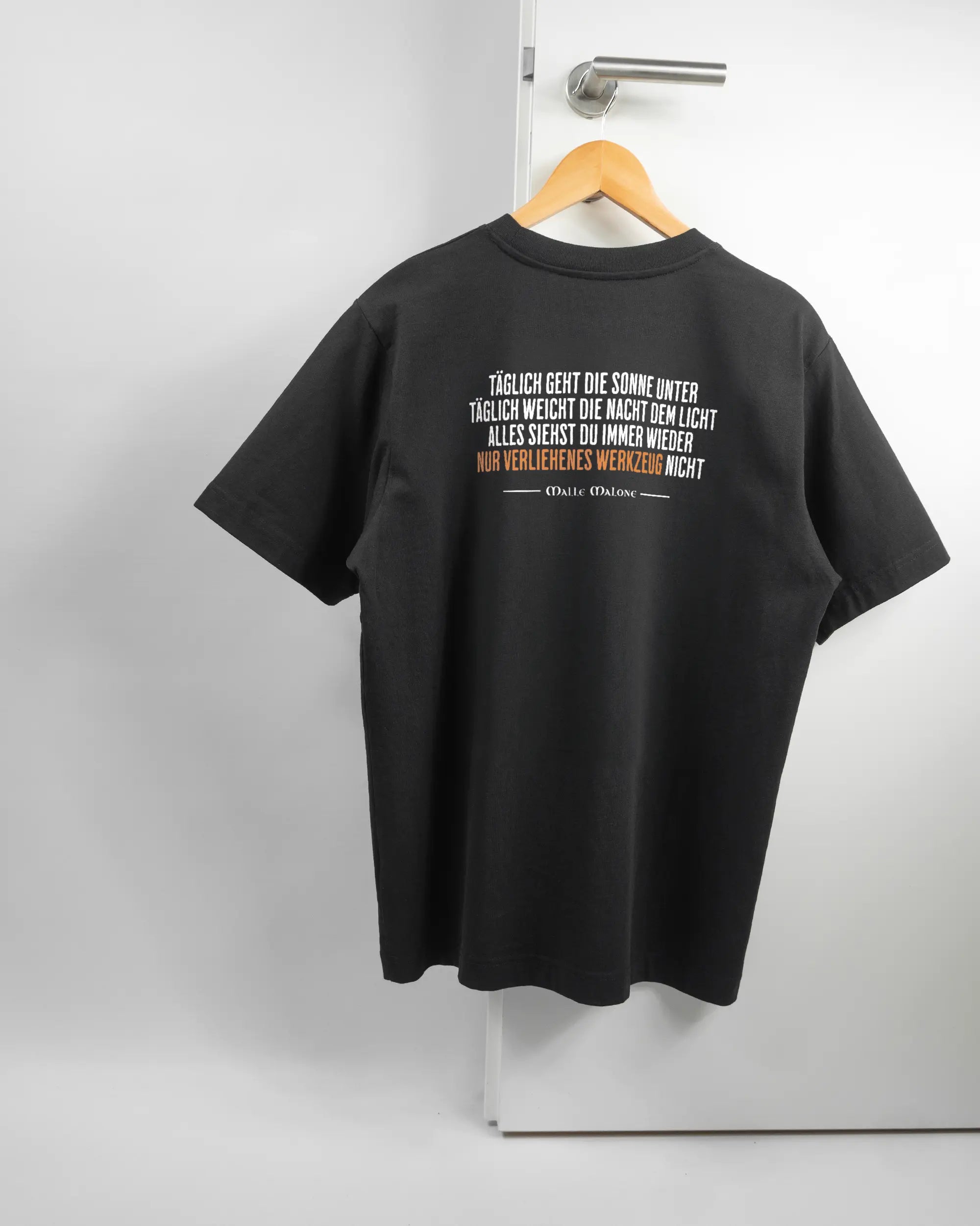 Rückseite des Organic Unisex T-Shirt Heavy Oversized von Maondo mit dem Design Wegzeug in der Farbe Black und in der Größe S auf einem Bügel an der Türklinke aufgehängt