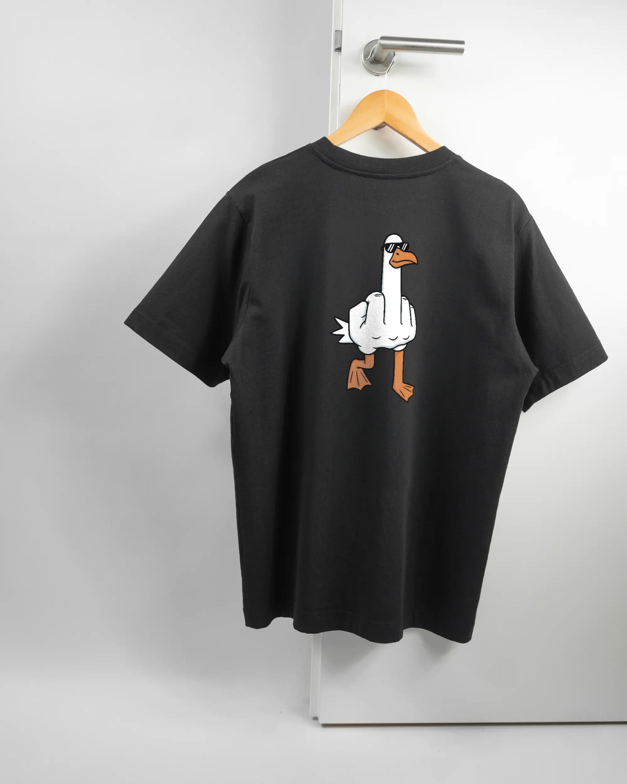 Rückseite des Organic Unisex T-Shirt Heavy Oversized von Maondo mit dem Design I give a duck in der Farbe Black und in der Größe S auf einem Bügel an der Türklinke aufgehängt