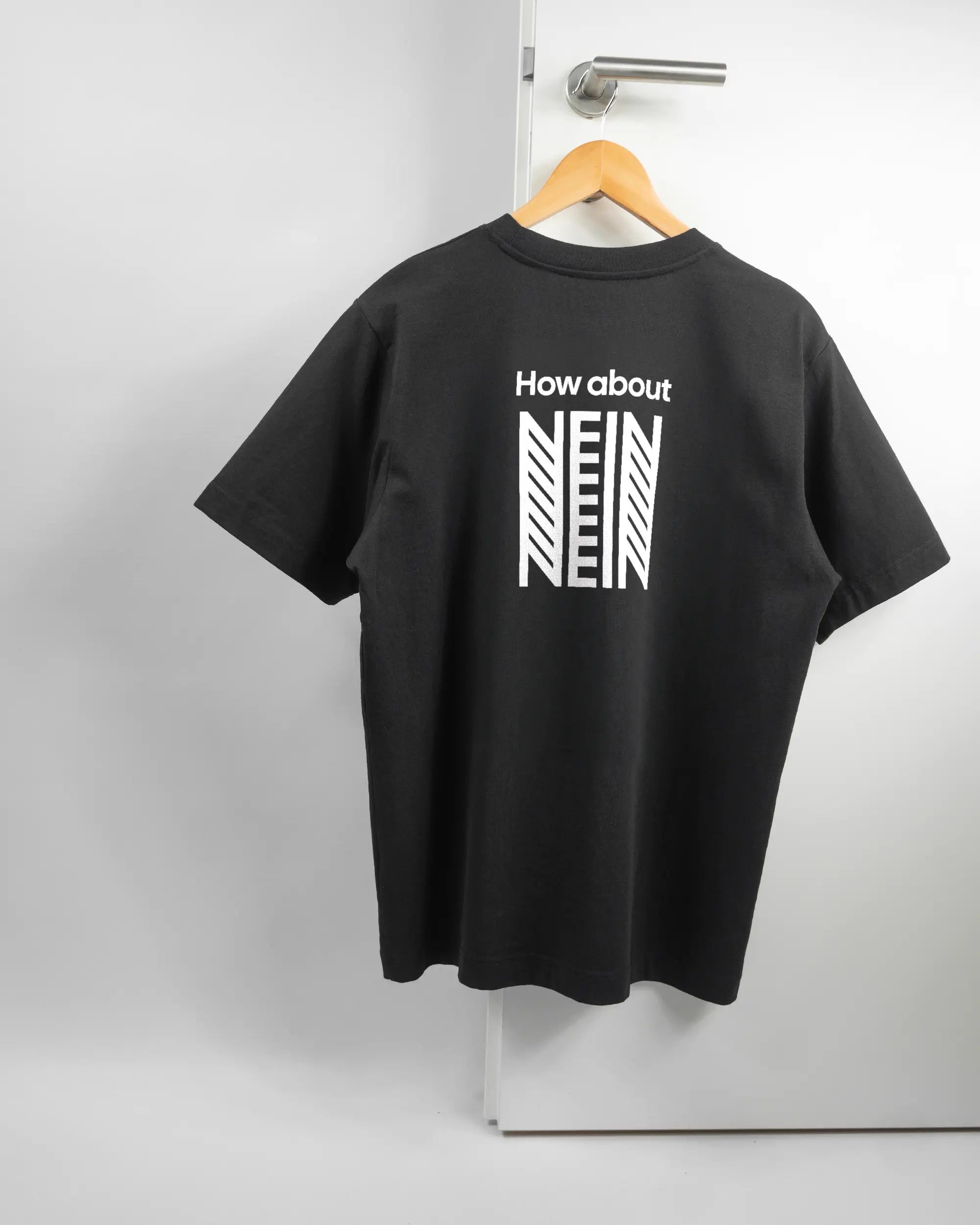 Rückseite des Organic Unisex T-Shirt Heavy Oversized von Maondo mit dem Design How about nein in der Farbe Black und in der Größe S auf einem Bügel an der Türklinke aufgehängt