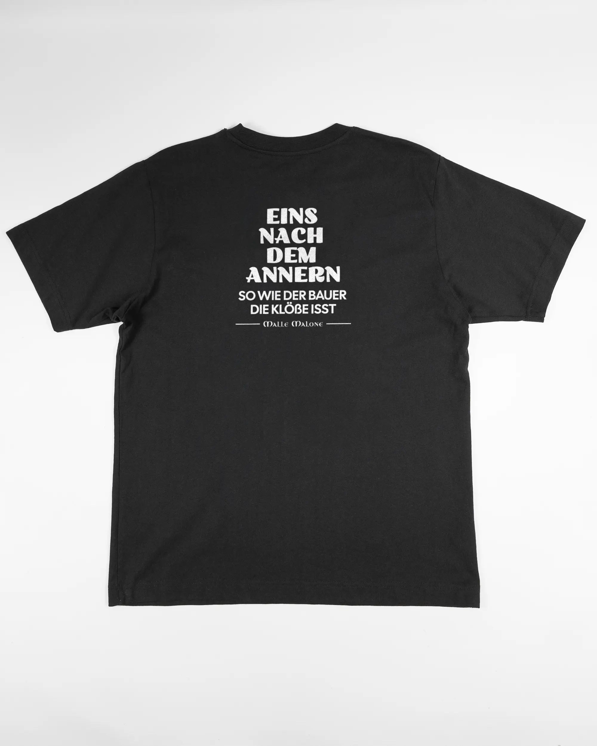 Rückseite des Organic Unisex T-Shirt Heavy Oversized von Maondo mit dem Design Eins nach dem Annern in der Farbe Black und in der Größe S flach auf den Boden gelegt
