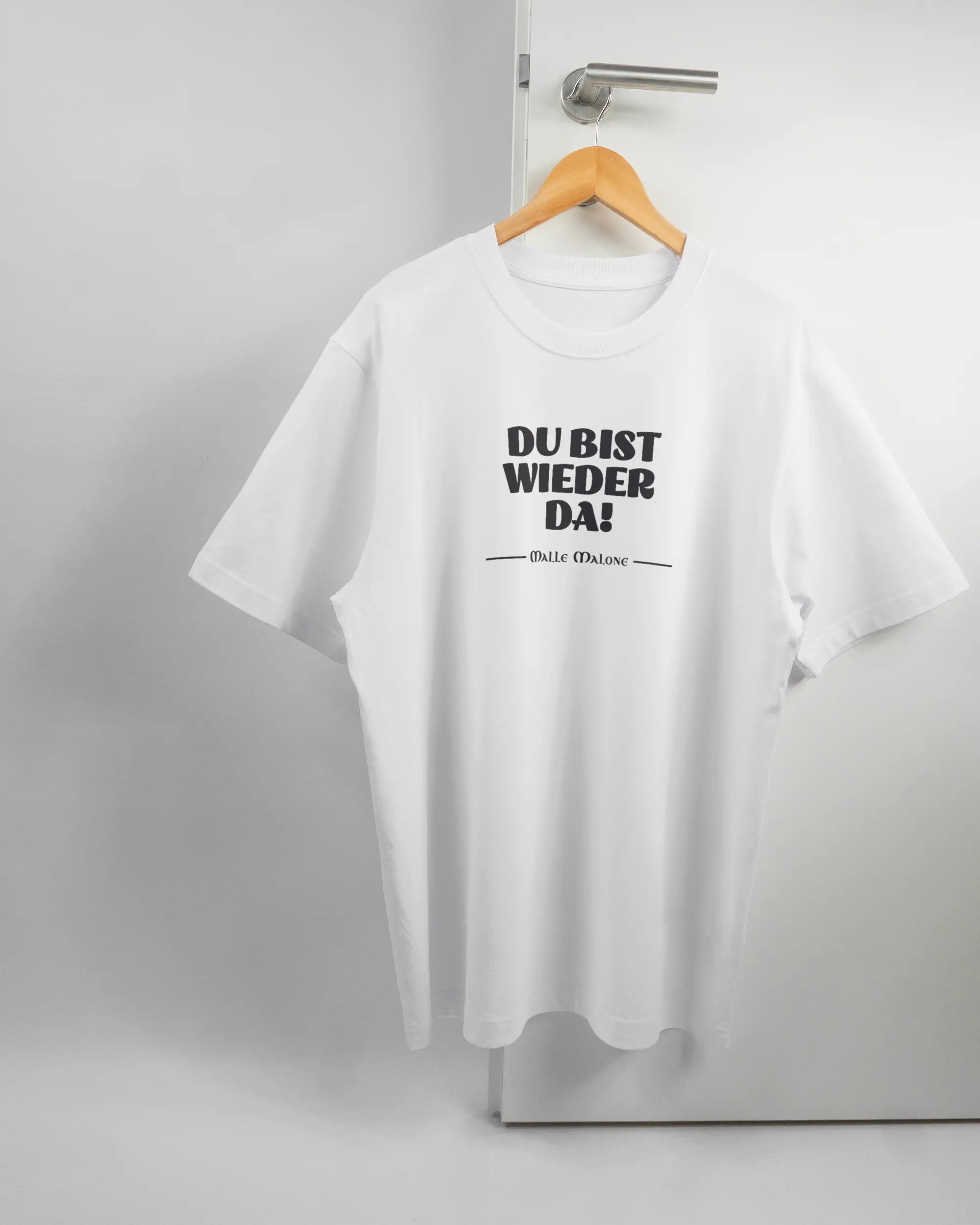Vorderseite des Organic Unisex T-Shirt Heavy Oversized von Maondo mit dem Design Wieder da in der Farbe White und in der Größe L auf einem Bügel an der Türklinke aufgehängt