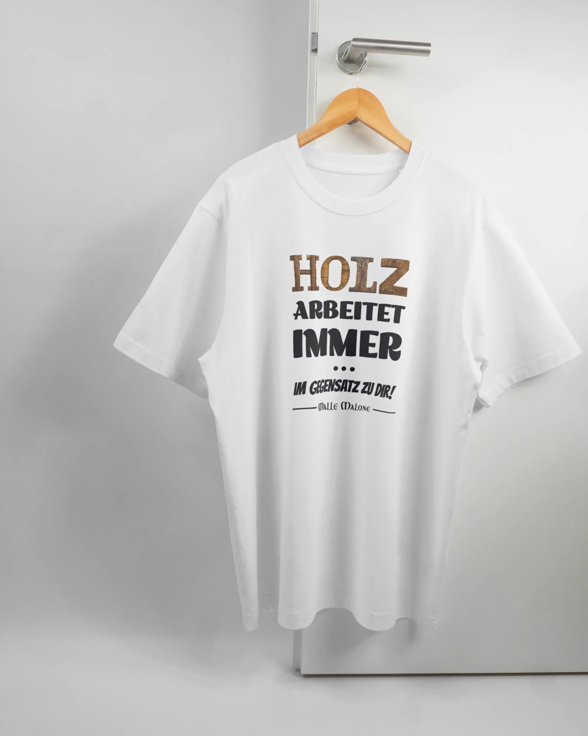 Vorderseite des Organic Unisex T-Shirt Heavy Oversized von Maondo mit dem Design Holzarbeit in der Farbe White und in der Größe L auf einem Bügel an der Türklinke aufgehängt