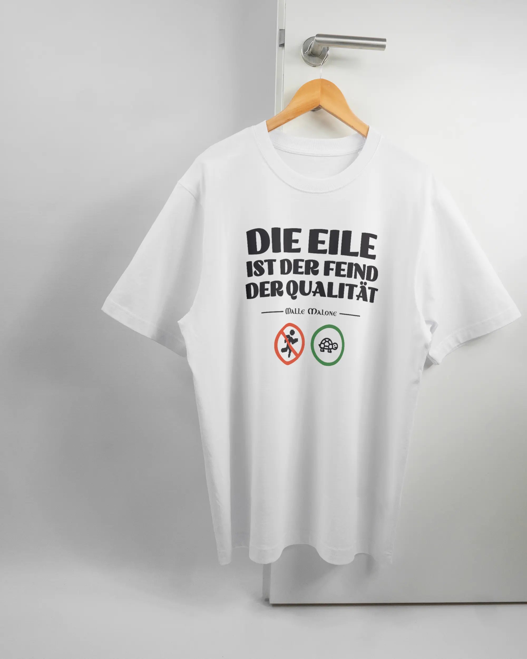 Vorderseite des Organic Unisex T-Shirt Heavy Oversized von Maondo mit dem Design Keine Eile in der Farbe White und in der Größe L auf einem Bügel an der Türklinke aufgehängt