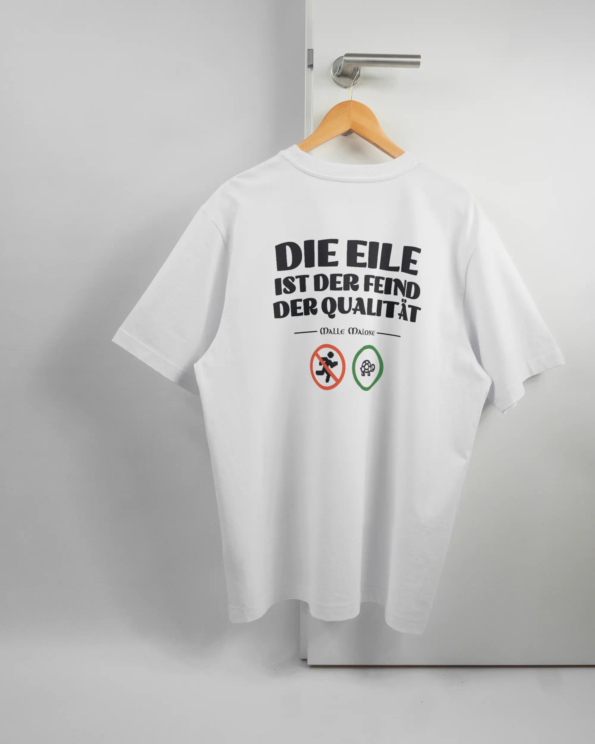 Rückseite des Organic Unisex T-Shirt Heavy Oversized von Maondo mit dem Design Keine Eile in der Farbe White und in der Größe L auf einem Bügel an der Türklinke aufgehängt