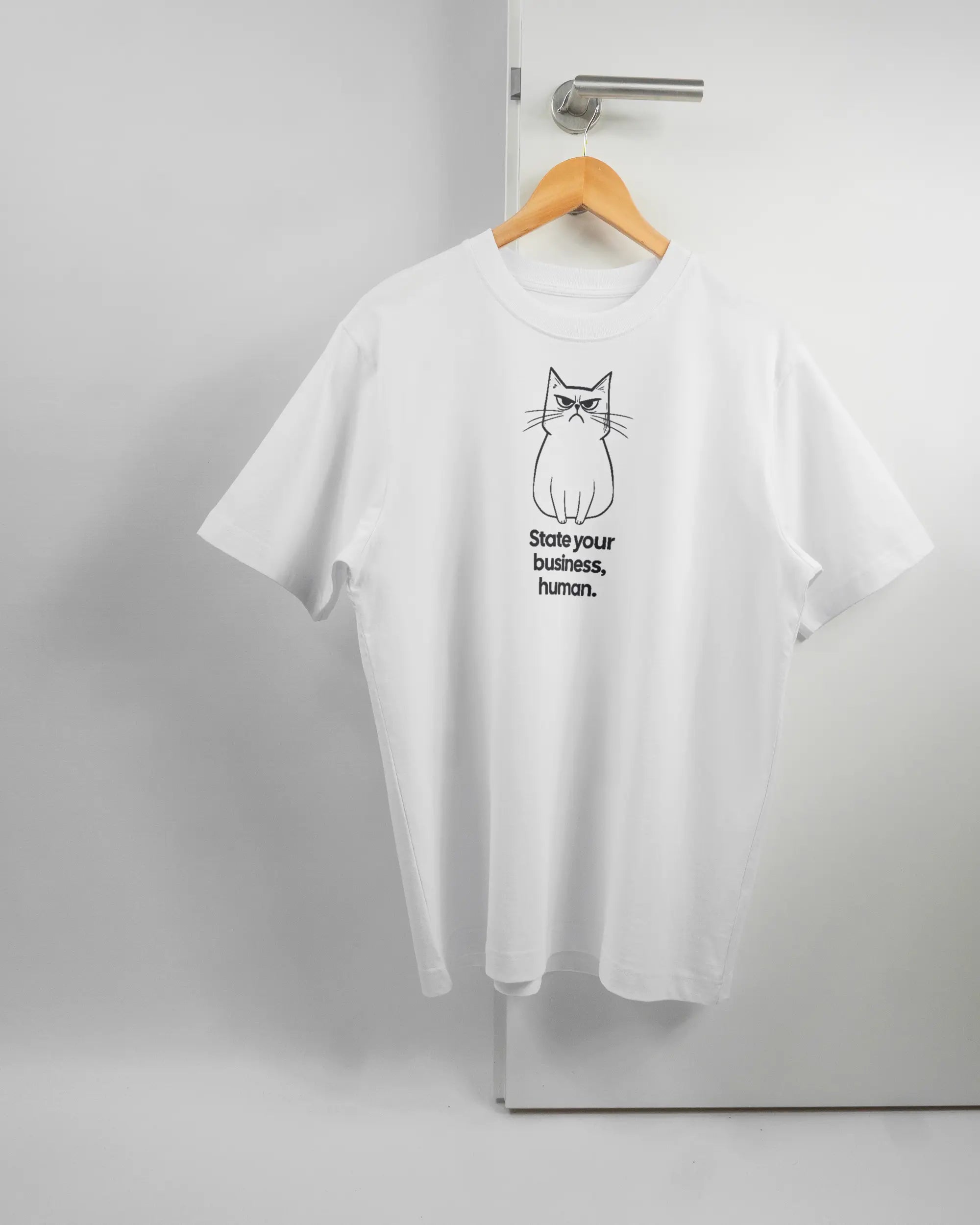 Vorderseite des Organic Unisex T-Shirt Heavy Oversized von Maondo mit dem Design Grumpy Purr in der Farbe White und in der Größe S auf einem Bügel an der Türklinke aufgehängt