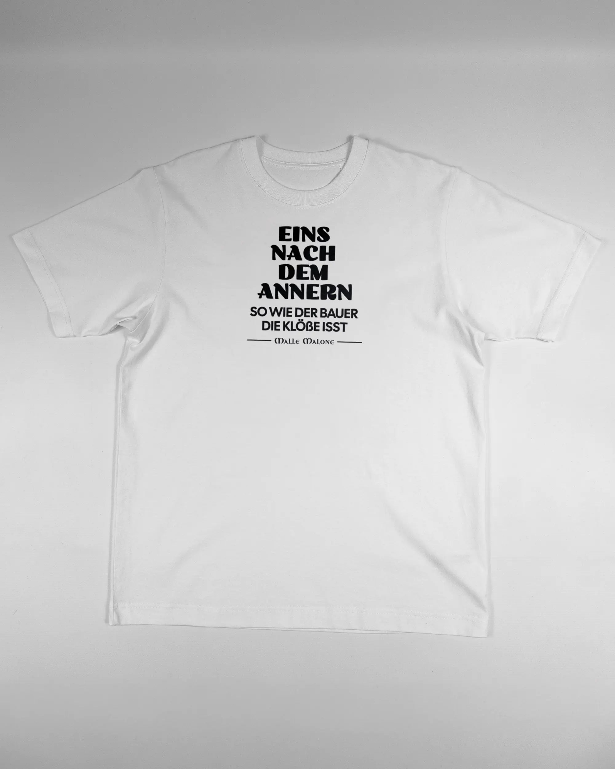 Vorderseite des Organic Unisex T-Shirt Heavy Oversized von Maondo mit dem Design Eins nach dem Annern in der Farbe White und in der Größe S flach auf den Boden gelegt