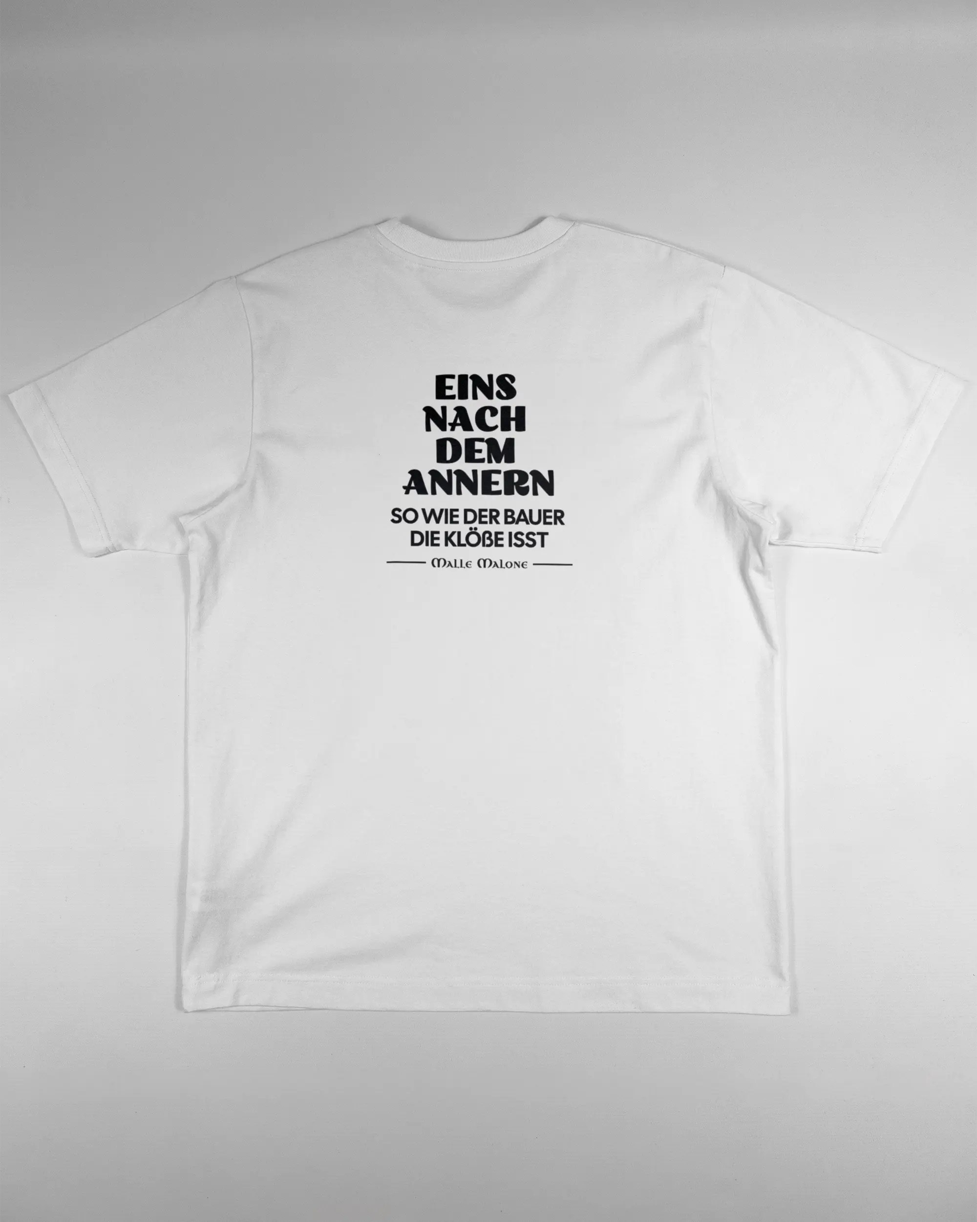 Rückseite des Organic Unisex T-Shirt Heavy Oversized von Maondo mit dem Design Eins nach dem Annern in der Farbe White und in der Größe S flach auf den Boden gelegt